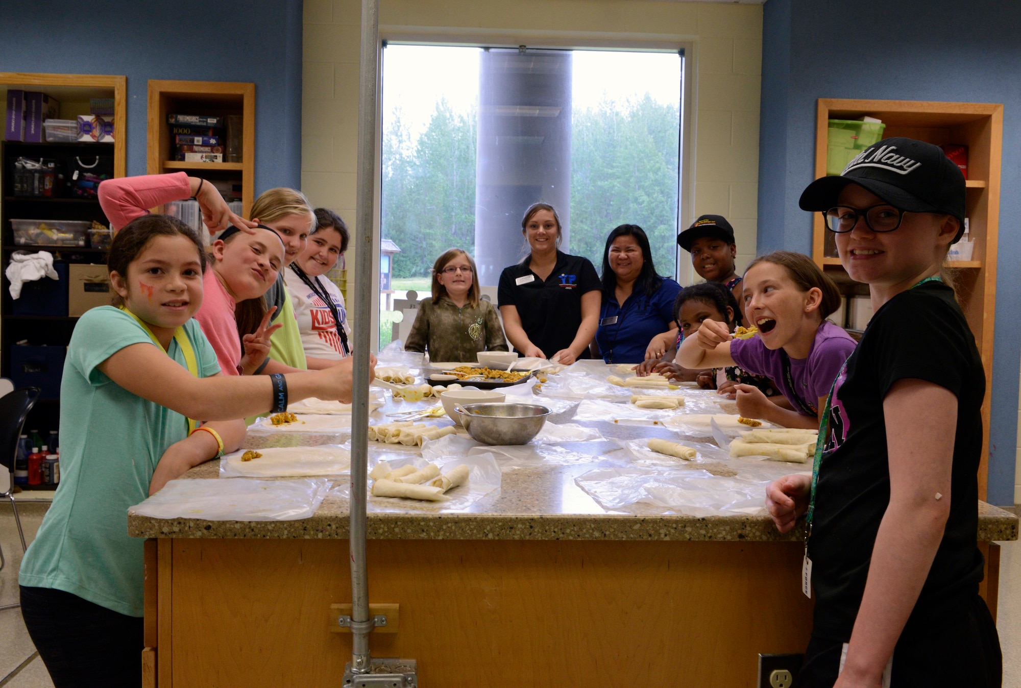 Cooking camp instructors and participants meet around the prep-table at the 2016 cooking camp, hosted at Two-Rivers Youth Center, at Joint Base Elmendorf-Richardson, Alaska, July 11, 2016. Participants learned various culinary techniques at the camp. (U.S. Air Force photo by Airman 1st Class Javier Alvarez)