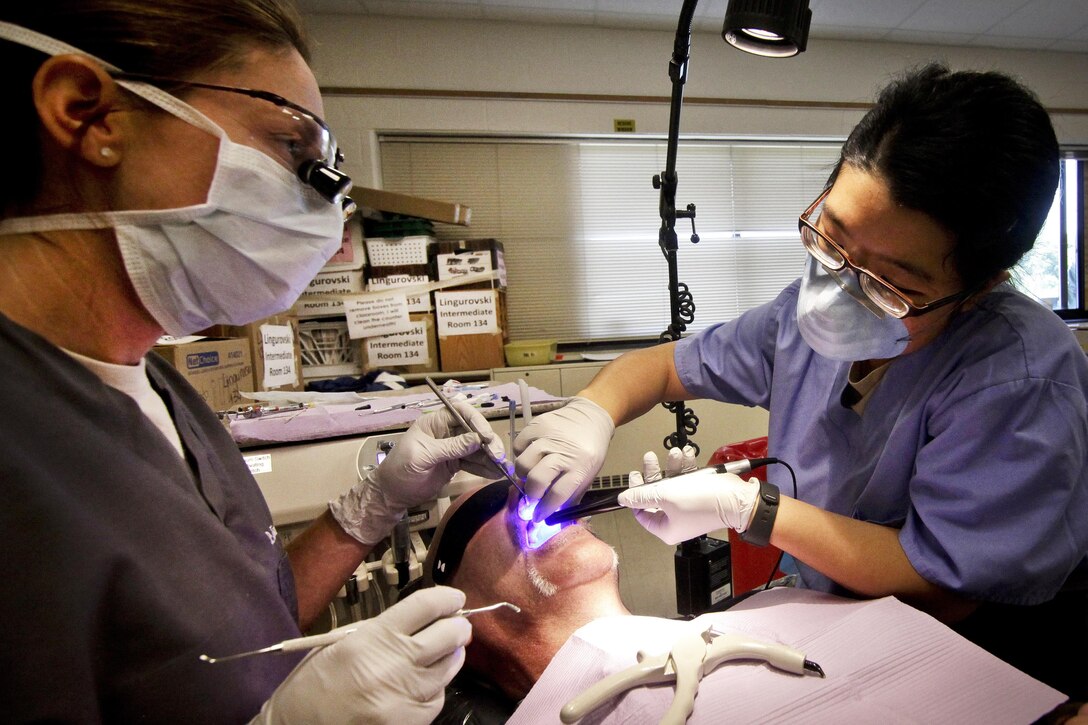 Air Force Maj. Jessica Bramlette, left, and Army Spc. Zhuhying Deng provide dental care to a patient during the Greater Chenango Cares Innovative Readiness Training at the Homer Intermediate School in Homer, N.Y., July 20, 2016. Bramlette is a dentist assigned to the New Jersey Air National Guard's 177th Medical Group. Deng is a dental assistant assigned to the Army Reserve's 7234th Medical Support Unit. Air National Guard photo by Tech. Sgt. Matt Hecht