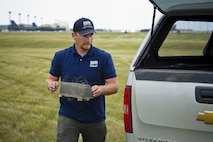 Dale Waites, U.S. Department of Agriculture wildlife biologist, carries a live trap in hopes of catching an American kestrel on the airfield at Minot Air Force Base, N.D., July 15, 2016. The birds nest on the airfield and are a hazard to the B-52H Stratofortress. They can cause damage to the engines of incoming and outgoing aircraft. (U.S. Air Force photo/Airman 1st Class J.T. Armstrong)