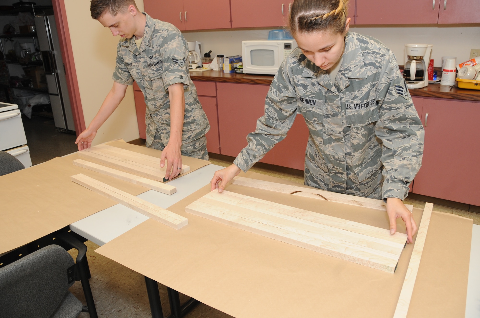 Senior Airman Natalie Kennon and Airman 1st Class Justice Fisher, 2nd Munitions Squadron commander support staff, place pieces of wood together to form a cutting board at the Wood Shop at Barksdale Air Force Base, La., July 18, 2016. The shop offers classes once a month to wood hobbyists who want to learn new skills. (U.S. Air Force photo/Airman Alexis C. Frost)