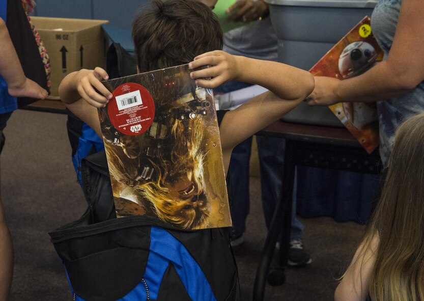 A child puts a folder into his new backpack during the Back to School Brigade, July 27, 2016, at Moody Air Force Base, Ga. Operation Homefront, a nonprofit organization, partnered with a local business to get members of the community involved by purchasing school supplies and donating them to military families. (U.S. Air Force photo by Airman 1st Class Janiqua P. Robinson) 