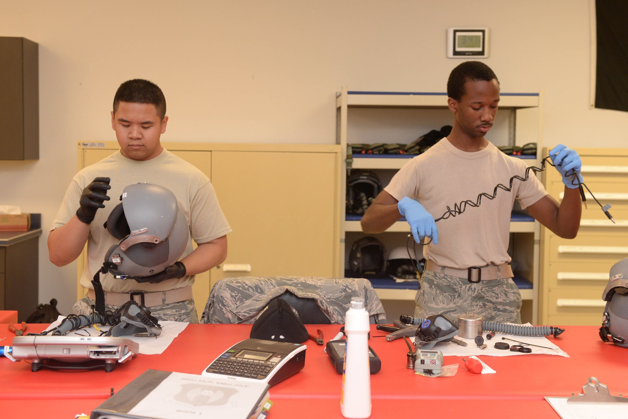 Airman 1st Class Bradley Fong, left, and Senior Airman Latron Robinson, aircrew flight equipment technicians from the 5th Operations Support Squadron, clean and inspect helmets at Minot Air Force Base, N.D., July 26, 2016.They inspected microphones, inhalation and exhalation valves, and helmet structure to ensure pilots have safe equipment. (U.S. Air Force photo/Airman 1st Class Jessica Weissman)