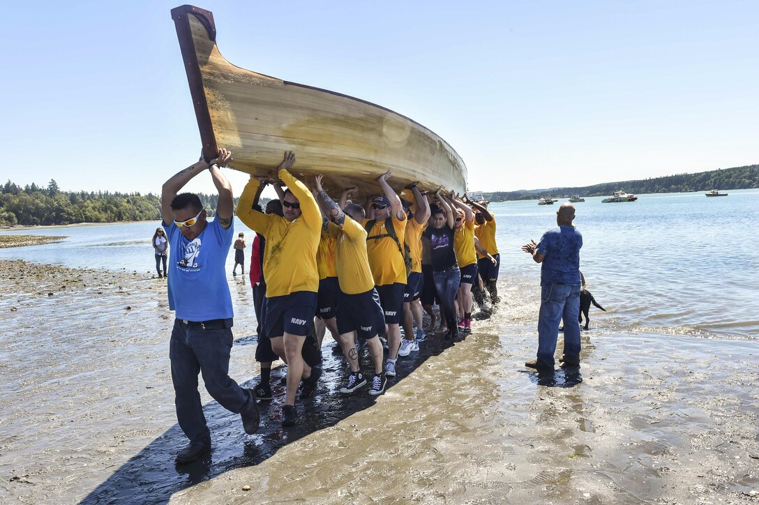 Sailors assist in transporting a tribal canoe, some weighing more than 1,500 pounds, during a canoe landing the Port Gamble S'Klallam Tribe hosted in Kingston, Wash., July 24, 2016. The sailors are assigned to Naval Base Kitsap. During the event, Pacific Northwest tribes traveled via canoe to tribal sites, culminating in a landing in Olympia, Wash. Navy photo by Petty Officer 2nd Class Cory Asato