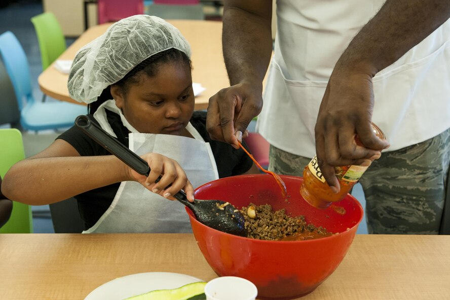 Phoenix, daughter of U.S. Air Force Staff Sgt. Christopher Clary, 23d Aircraft Maintenance Squadron crew chief, mixes ingredients together during a youth cooking camp, July 26, 2016, at Moody Air Force Base, Ga. During the camp, children learned to cook a variety of dishes including: Italian stuffed zucchini, chicken cordon bleu and rainbow cheesecake. (U.S. Air Force photo by Airman 1st Class Lauren M. Hunter)
