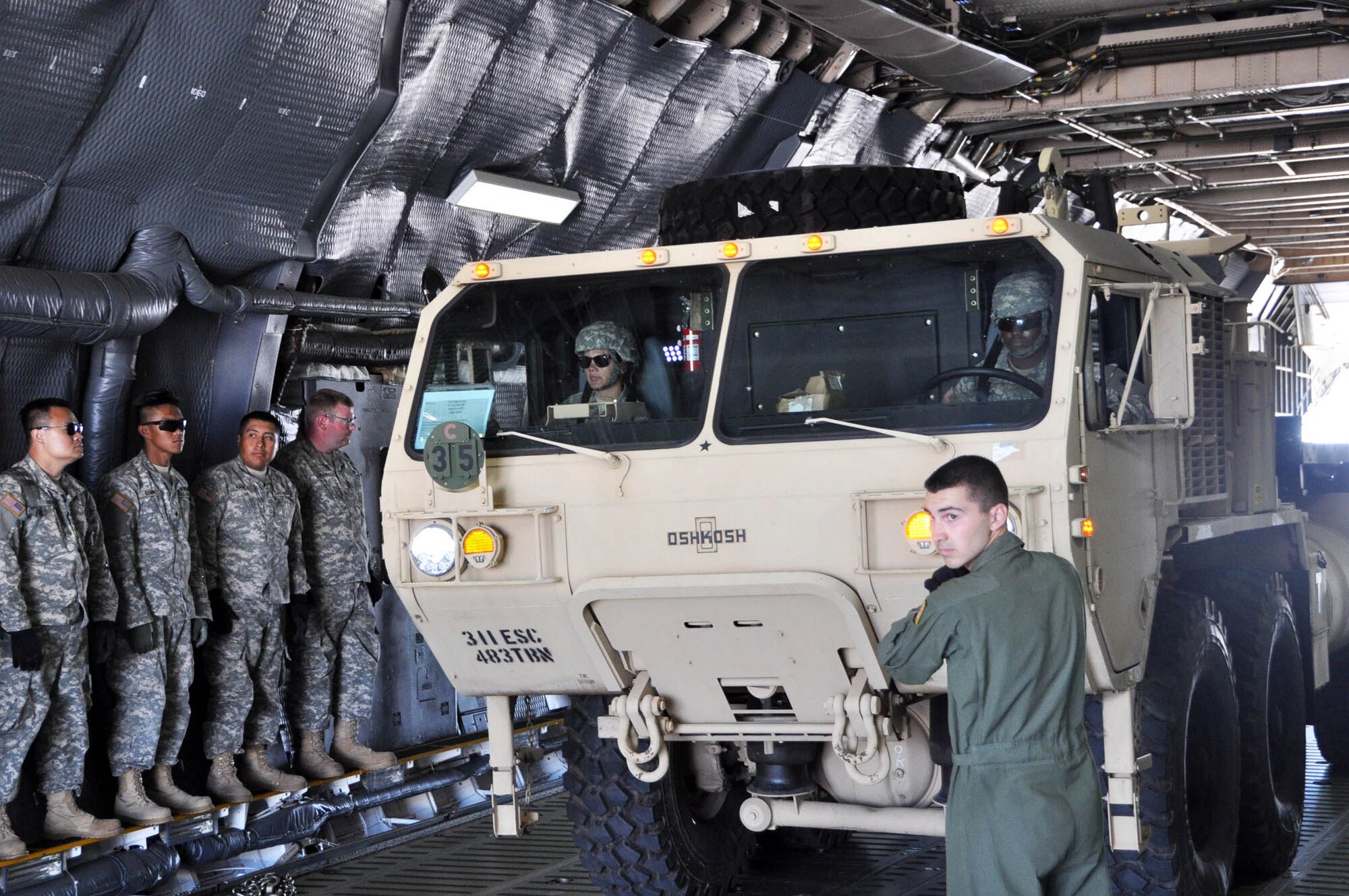 Senior Airman Kyle Alcantara, a loadmaster with the 312th Airlift Squadron guides a tactical vehicle driven by a member of the 238th Transportation Company from the Military Ocean Terminal in Concord, Calif., off of a C-5 Galaxy cargo aircraft, during exercise PATRIOT WYVERN, July 23, 2016. The PATRIOT WYVERN exercises are hands-on, bi-annual events conducted by the 349th Air Mobility Wing designed to hone combat skills and improve organizational interoperability. The code name "Patriot" is common to many Air Force Reserve led exercises, such as Operation PATRIOT EXPRESS. The wyvern name derives from the mythical winged creature found on the 349th AMW's unit crest. (U.S. Air Force photo by Staff Sgt. Cindy G. Alejandrez)