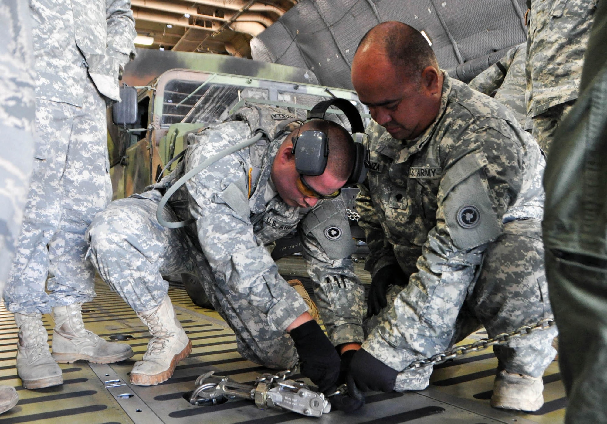 Specialists Eduardo Valenzuela and Leo Desouza, with the 238th Transportation Company from the Military Ocean Terminal in Concord, Calif., learn to secure a chain to a C-5 Galaxy cargo aircraft July 23, 2016. The Soldiers were learning from the aerial port personnel part of the 349th Air Mobility Wing during exercise PATRIOT WYVERN at Travis Air Force Base Calif. The PATRIOT WYVERN exercises are hands-on, bi-annual events conducted to hone combat skills and improve organizational interoperability. The code name "Patriot" is common to many Air Force Reserve led exercises, such as Operation PATRIOT EXPRESS. The wyvern name derives from the mythical winged creature found on the 349th AMW's unit crest. (U.S. Air Force photo by Staff Sgt. Cindy G. Alejandrez)