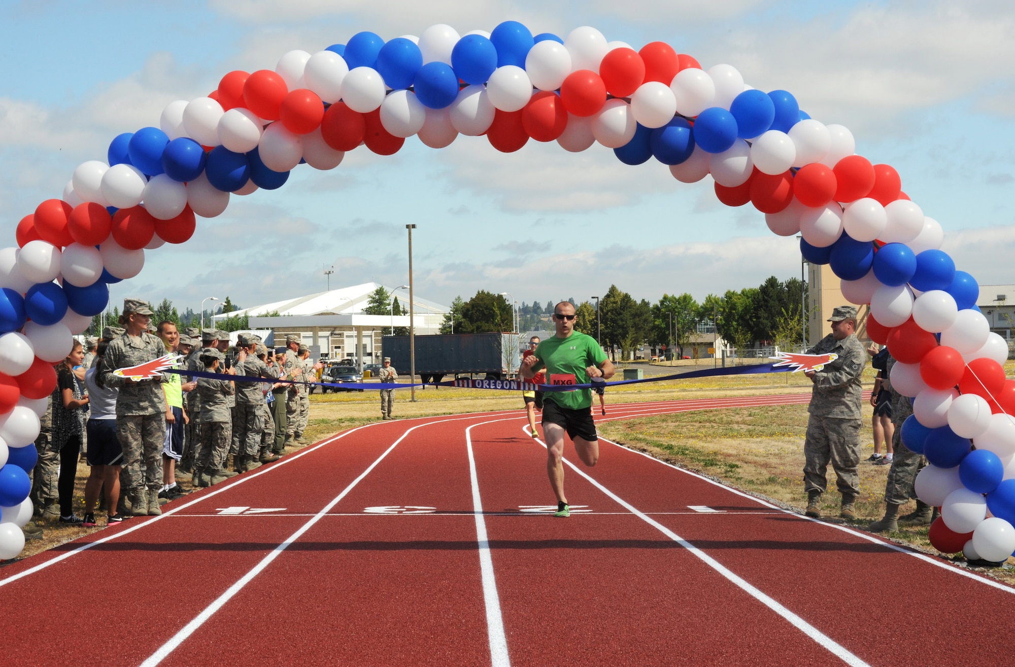 Oregon Air National Guard Staff Sgt. Alan Plank, assigned to the 142nd Fighter Wing Maintenance Group, crosses the finishing line and cuts the ceremony opening ribbon during the inaugural first race on the new track at the Portland Air National Guard Base, Ore., July 26, 2016. (U.S. Air National Guard photo by Tech. Sgt. John Hughel, 142nd Fighter Wing Public Affairs/Released)