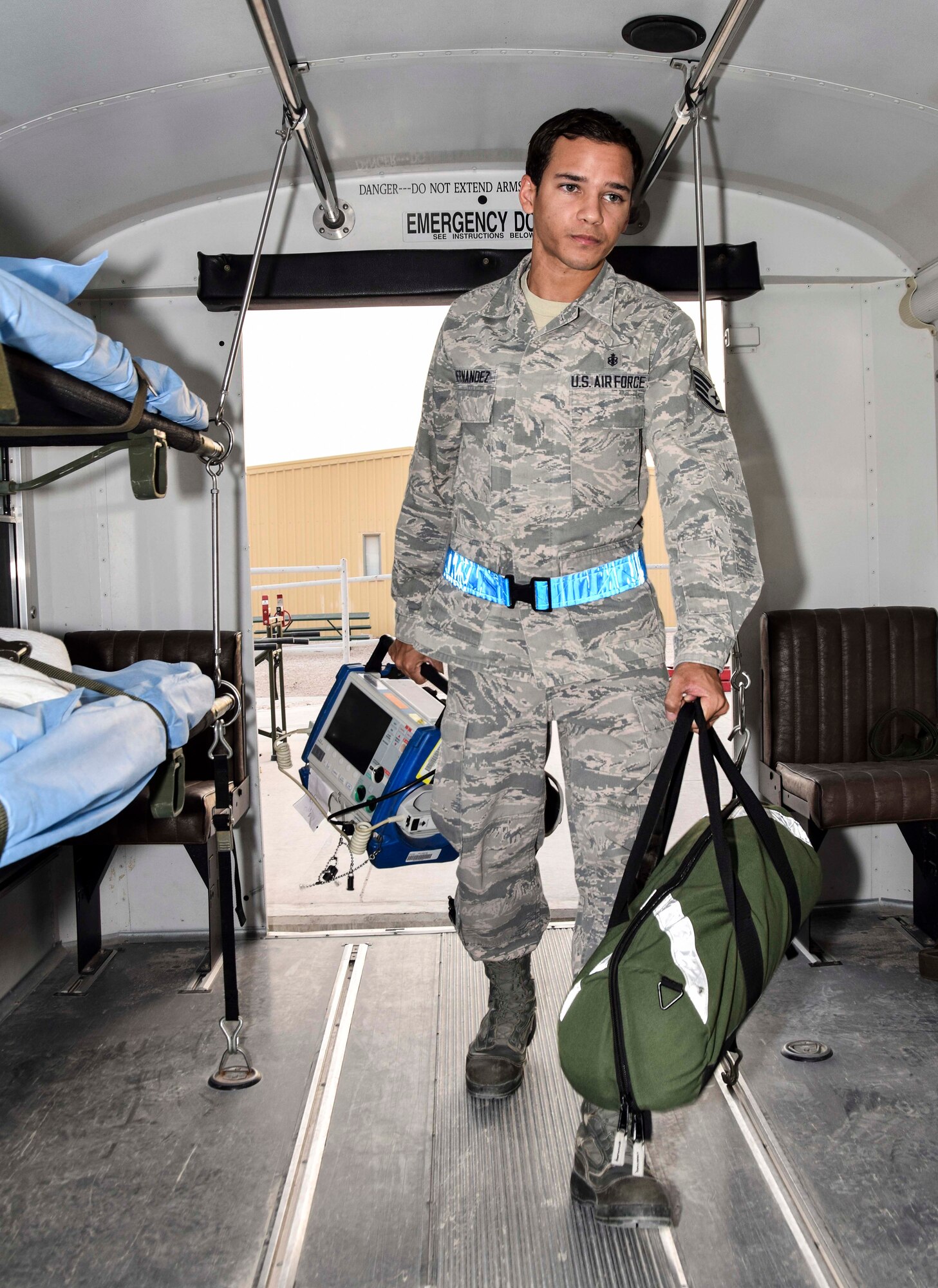 Staff Sgt. Luis Hernandez, a medical technician with the 379th Enroute Patient Staging Facility, carries an Zoll monitor/defibrillator used to monitor the cardiovascular status of a patient and for emergency management of a cardiac dysrythmia and a bag with airway and breathing supplies on July 18, 2016 at Al Udeid Air Base, Qatar. Hernandez and the staff of the EPSF prepared a bus to carry 14 patients and a military working dog and his handler transitting through the area of responsibility on their way to advanced care in Germany.  (U.S.Air Force photo/Technical Sgt. Carlos J. Trevino/Released) 