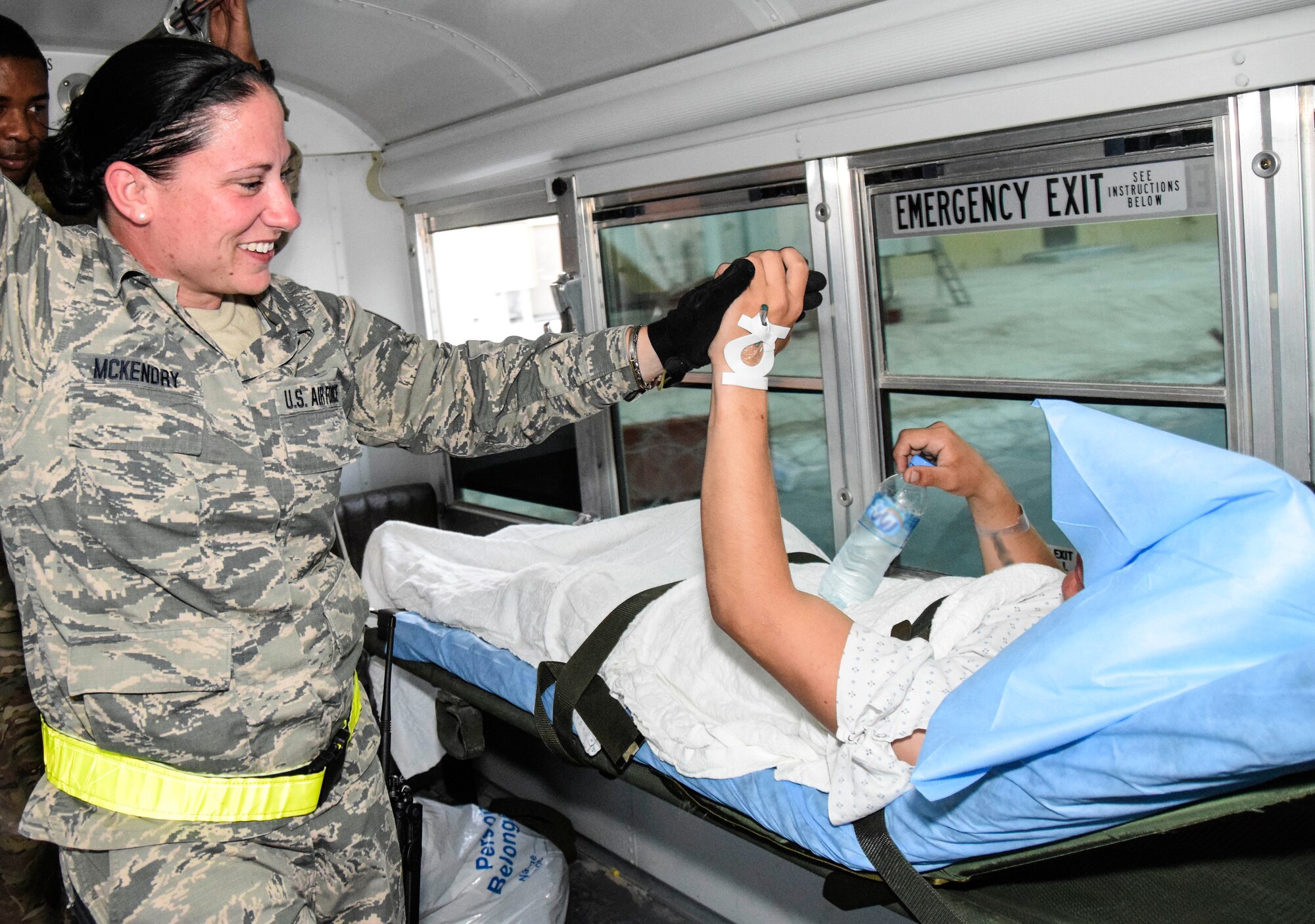 With a high five of reassurance, Staff Sgt. Jennifer McKendry, 379th Enroute Patient Staging Facility medical technician, comforts a patient with a on an ambulance July 18, 2016, from Al Udeid Air Base, Qatar.  The Soldier on the stretcher was one of 14 military members, including a military working dog, sent to Landstuhl Regional Medical Center in Germany for a higher level of treatment. (U.S. Air Force photo/Technical Sgt. Carlos J. Treviño)