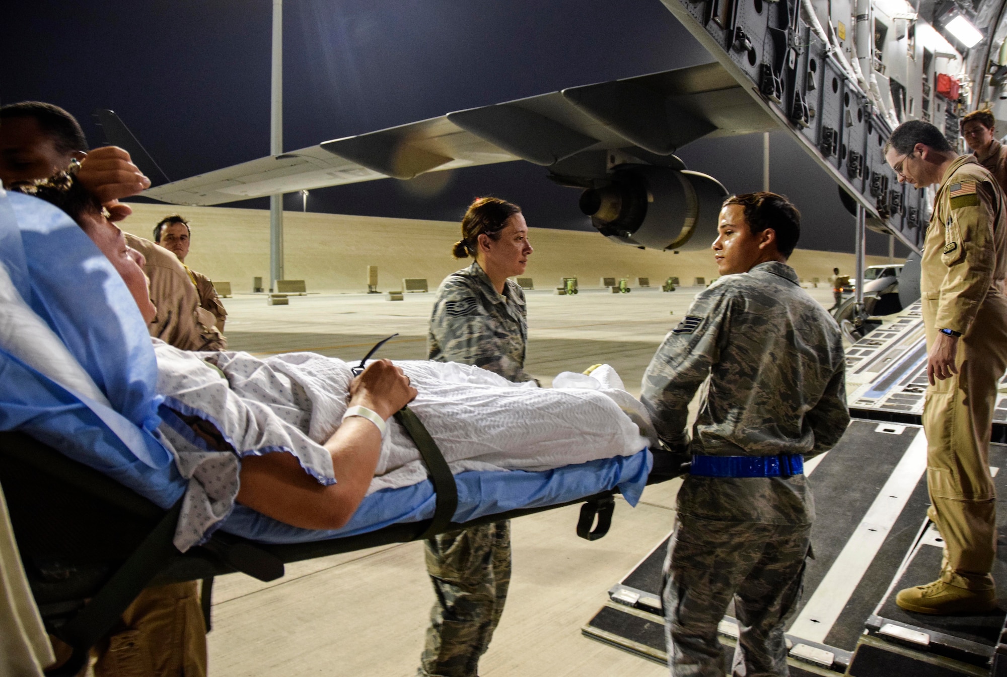 Technical Sgt. Erin Trueblood (top left) and Staff Sgt. Luis Hernandez, 379th Enroute Patient Staging Facility medical technicians, load a patient onto a C-17 Globemaster III July 18, 2016, from Al Udeid Air Base, Qatar.  The patients were enroute to Landstuhl Regional Medical Center in Germany for a higher level of care. (U.S. Air Force photo/Technical Sgt. Carlos J. Treviño)
