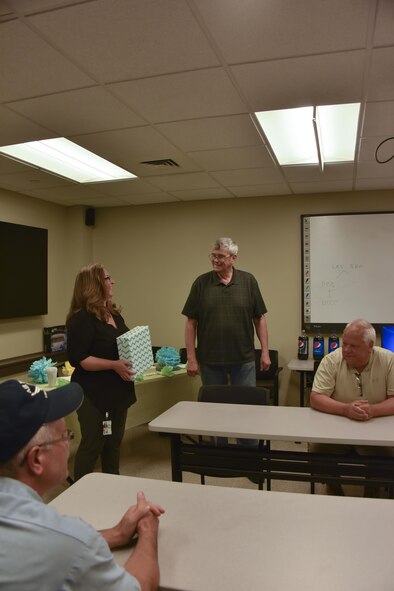George Kelly, vehicle maintenance manager, receives his retirement gift from Carrie Gernhardt, project manager for Maytag Aircraft Corporation, at the Pittsburgh International Air Reserve Station, Pennsylvania, July 26, 2016. Kelly is retiring after 37 years at the 911th Airlift Wing. (U.S. Air Force courtesy photo by Ashley Podrasky) 