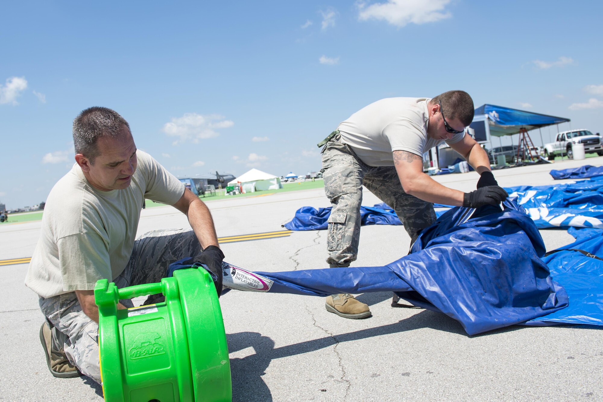 Senior Master Sgt. Charles Hoover, 434th Aircraft Maintenance Squadron flight chief, secures an airline to a blower as Tech. Sgt. Derek Nolley, 434th MXS electronics environmental specialist, unfolds an rapidly inflating tent at the Dayton Vectron Airshow in Dayton, Ohio, June 17, 2016.  The tent is used to house the static displays, Airmen and visitors during the air show. (U.S. Air Force photo/Tech. Sgt. Benjamin Mota)