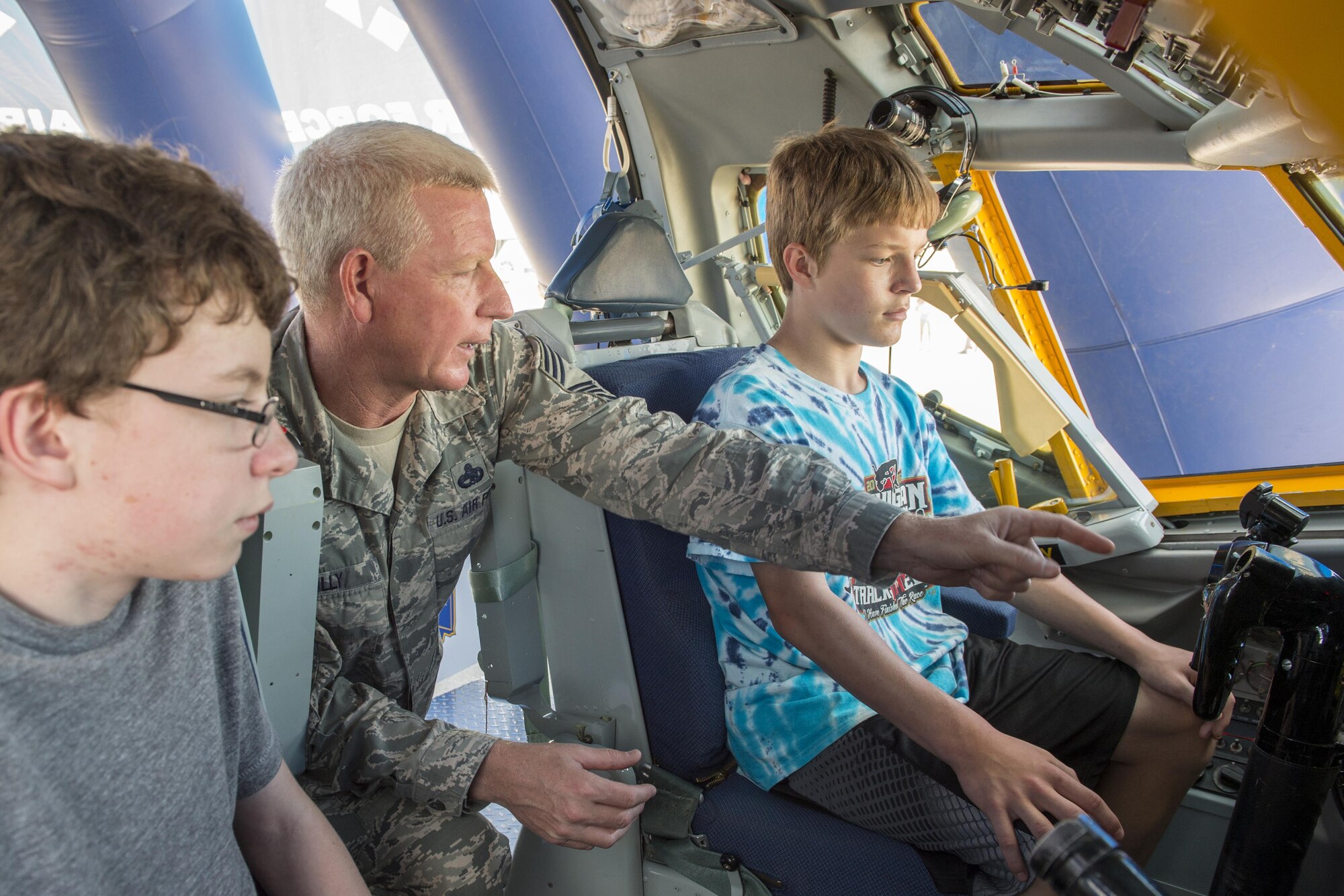 Chief Master Sgt. Richard Scully, 434th Maintenance Group quality assurance superintendent, explains the controls of a KC-135R Stratotanker interactive flight deck to Hunter Globe, left, and Harrison Pierce, both airshow visitors from Ann Arbor, Michigan, at the Dayton Vectron Airshow in Dayton, Ohio, June 18, 2016. During the event, Scully and five other Airmen volunteered to setup up and operate the displays while sharing their military knowledge with visitors. (U.S. Air Force photo/Tech. Sgt. Benjamin Mota)