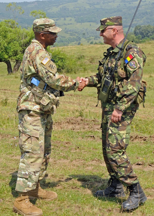 Army Sgt. 1st Class Allen Lurdell shakes hands with Romanian army Maj. Adrian Ranga during Exercise Saber Guardian 16 at the Romanian Land Force Combat Training Center in Cincu, Romania, July 28, 2016. Army photo by Staff Sgt. Corinna Baltos