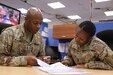 Army Chief Warrant Officer 3 Thomas E. Perry III, mobility officer with the 1st Sustainment Command (Theater), assists Army Sgt. 1st Class Jace V. Morman, sustainment cell noncommissioned officer with the 1st TSC, with her warrant officer packet. (U.S. Army Reserve photo by Sgt. 1st Class Naurys Marte/Released)