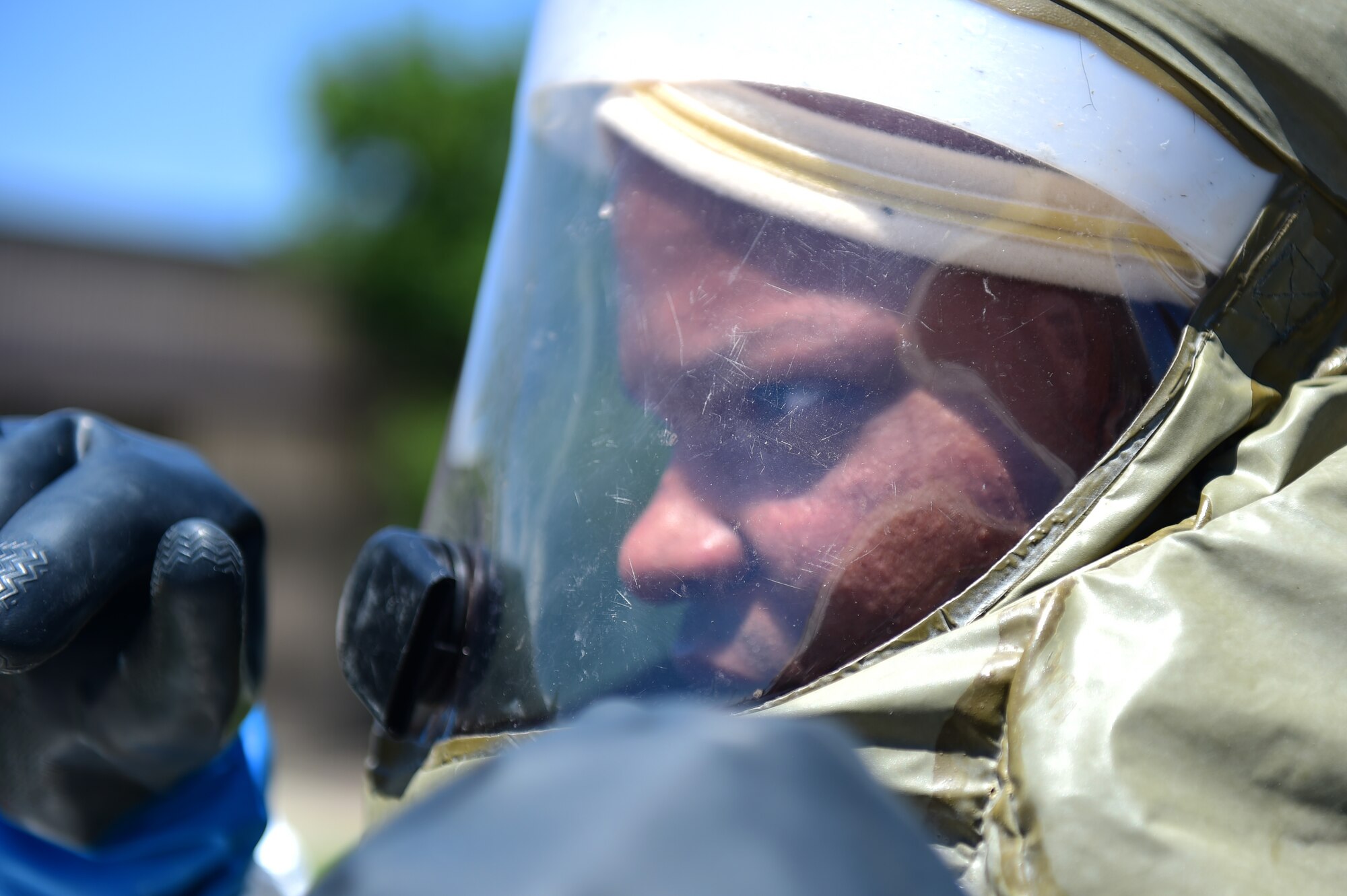 A member of the 460th Medical Group in-place patient decontamination triage and manpower/security team waits as another team member fixes part of his decontamination suit July 21, 2016, during a simulated exercise on Buckley Air Force Base, Colo. The 19-person IPPD team performed a final timed exercise, where the goal was to decontaminate mock casualties from a simulated terrorist attack using a weapon of mass destruction. (U.S. Air Force photo by Airman 1st Class Gabrielle Spradling/Released)