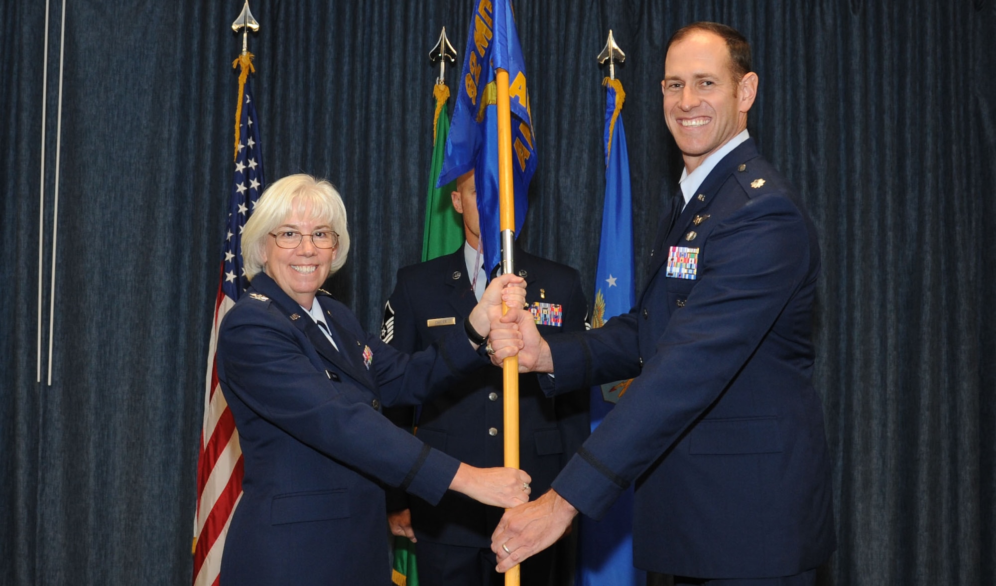 Col. Margaret Carey, 92nd Medical Group commander, passes the 92nd Aerospace Medicine Squadron guidon to Lt. Col. Kenneth Bode, 92nd AMDS commander, during the assumption of command ceremony July 27, 2016, at Fairchild Air Force Base, Wash. Bode was previously commander of 8th Medical Operations Squadron, Kunsan Air Base, South Korea. (U.S. Air Force photo/Senior Airman Sam Fogleman)
