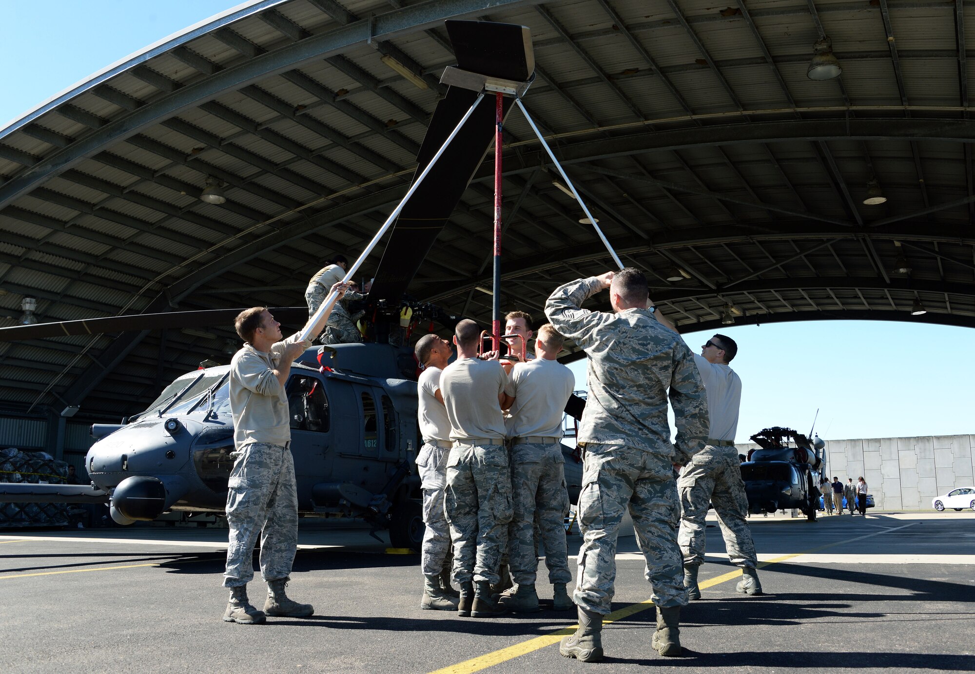 Members of the 129th Rescue Wing maintenance squadron unfold the main blades of an HH-60 Pavehawk shortly after its arrival at Royal Australian Air Force base Townsville for operation Angel Reign, June 28, 2016. The 129th MXS unfolded a total of two helicopters which were later used for multiple exercise missions alongside pararescuemen.   (U.S. Air National Guard photo by Senior Airman Zachiah Roberson/released)