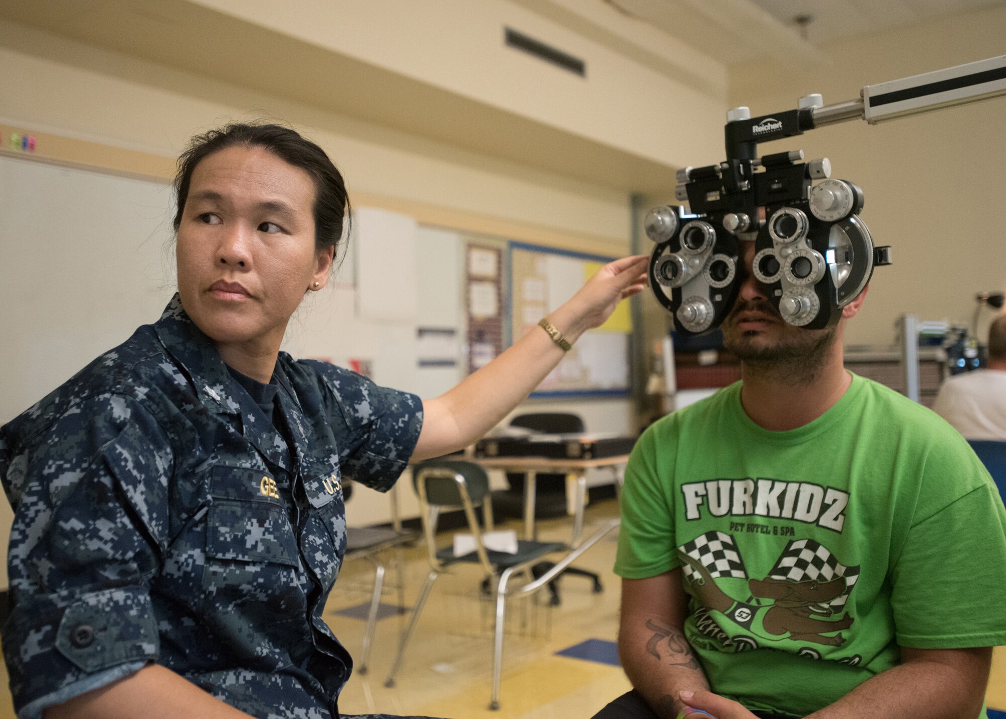 U.S. Navy Cmdr. Sharlene Gee, an optometrist with Expeditionary Medical Facility Camp Pendleton, performs a vision test for a Western Kentucky resident at Paducah Tilghman High School in Paducah, Ky., July 18, 2016, during Bluegrass Medical Innovative Readiness Training. The Kentucky Air National Guard, U.S. Navy Reserve and other military units are teaming with the Delta Regional Authority to offer medical and dental care at no cost to residents in three Western Kentucky locations from July 18 to 27 as part of the training event. (U.S. Air National Guard photo by Master Sgt. Phil Speck)