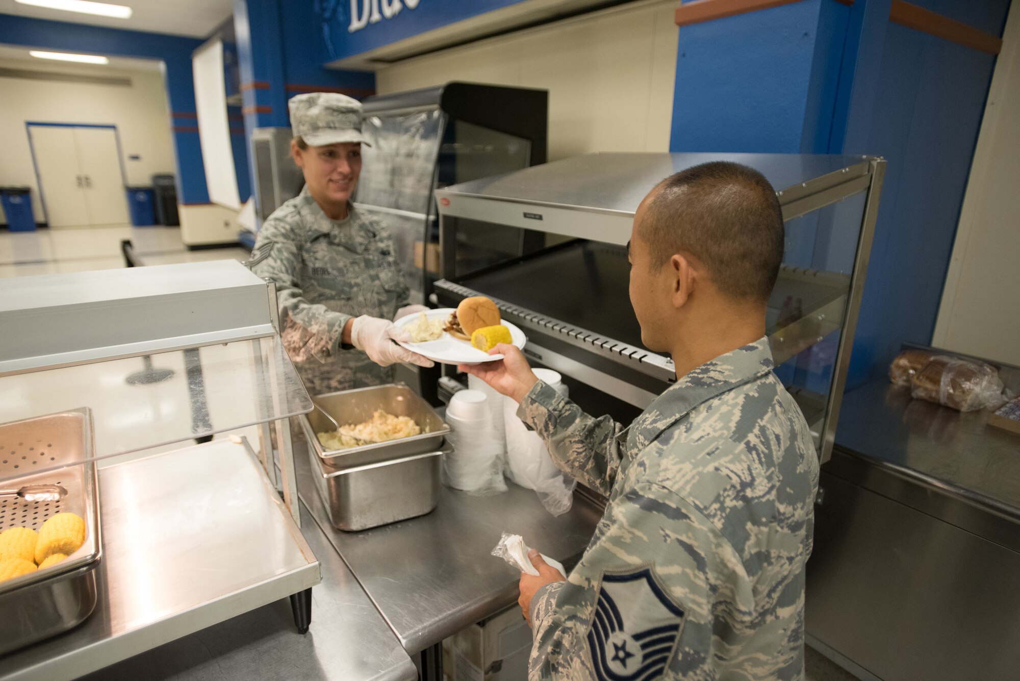 U.S. Air Force Tech. Sgt. Amanda Bedel (left), a food services specialist from the Kentucky Air National Guard’s 123rd Force Support Squadron, serves lunch to Master Sgt. Bao Huyhn at Paducah Tilghman High School in Paducah, Ky., July 20, 2016, during Bluegrass Medical Innovative Readiness Training. The Kentucky Air National Guard, U.S. Navy Reserve and other military units are teaming with the Delta Regional Authority to offer medical and dental care at no cost to residents in Paducah and two other Western Kentucky locations from July 18 to 27 as part of the training event. (U.S. Air National Guard photo by Master Sgt. Phil Speck)