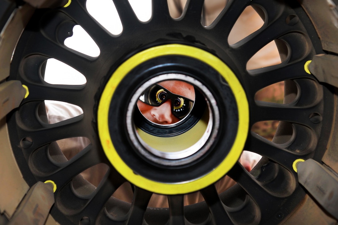 Air Force Staff Sgt. Michael Patterson looks through the center of a C-130J Hercules main landing gear at Camp Lemonnier, Djibouti, July 18, 2016. Patterson is an aerospace propulsion craftsman assigned to the 81st Expeditionary Rescue Squadron. Air Force photo by Staff Sgt. Benjamin Raughton