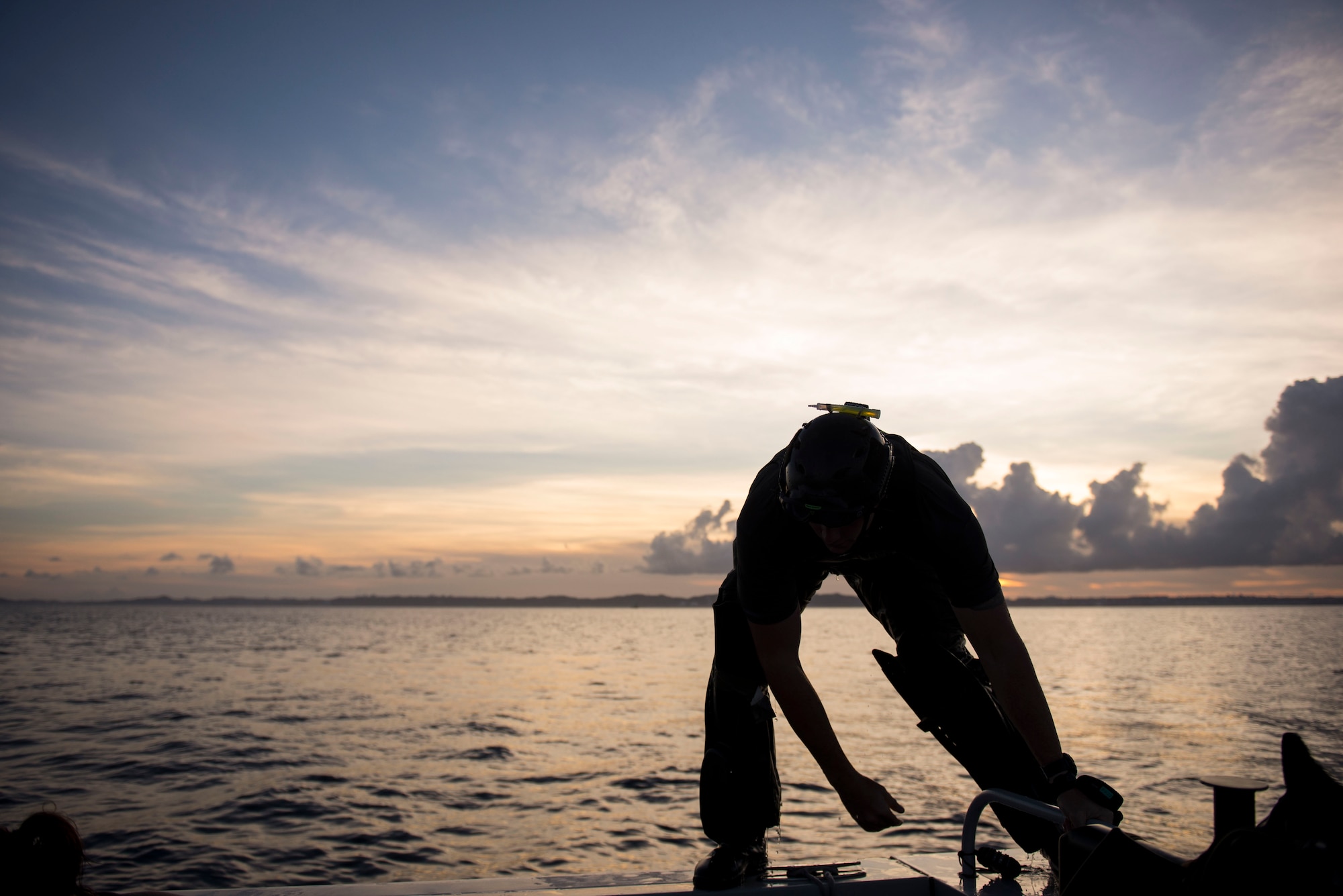 A U.S. Air Force pararescueman climbs aboard a boat after performing a static line jump as the sun sets after a lowlight training operation in the Pacific Ocean June 29, 2016. Air Force pararescue is one of the United States Department of Defense’s elite combat forces trained and equipped to conduct personnel rescue and recovery in both conventional and unconventional combat rescue operations. (U.S. Air Force photo by Senior Airman Omari Bernard)