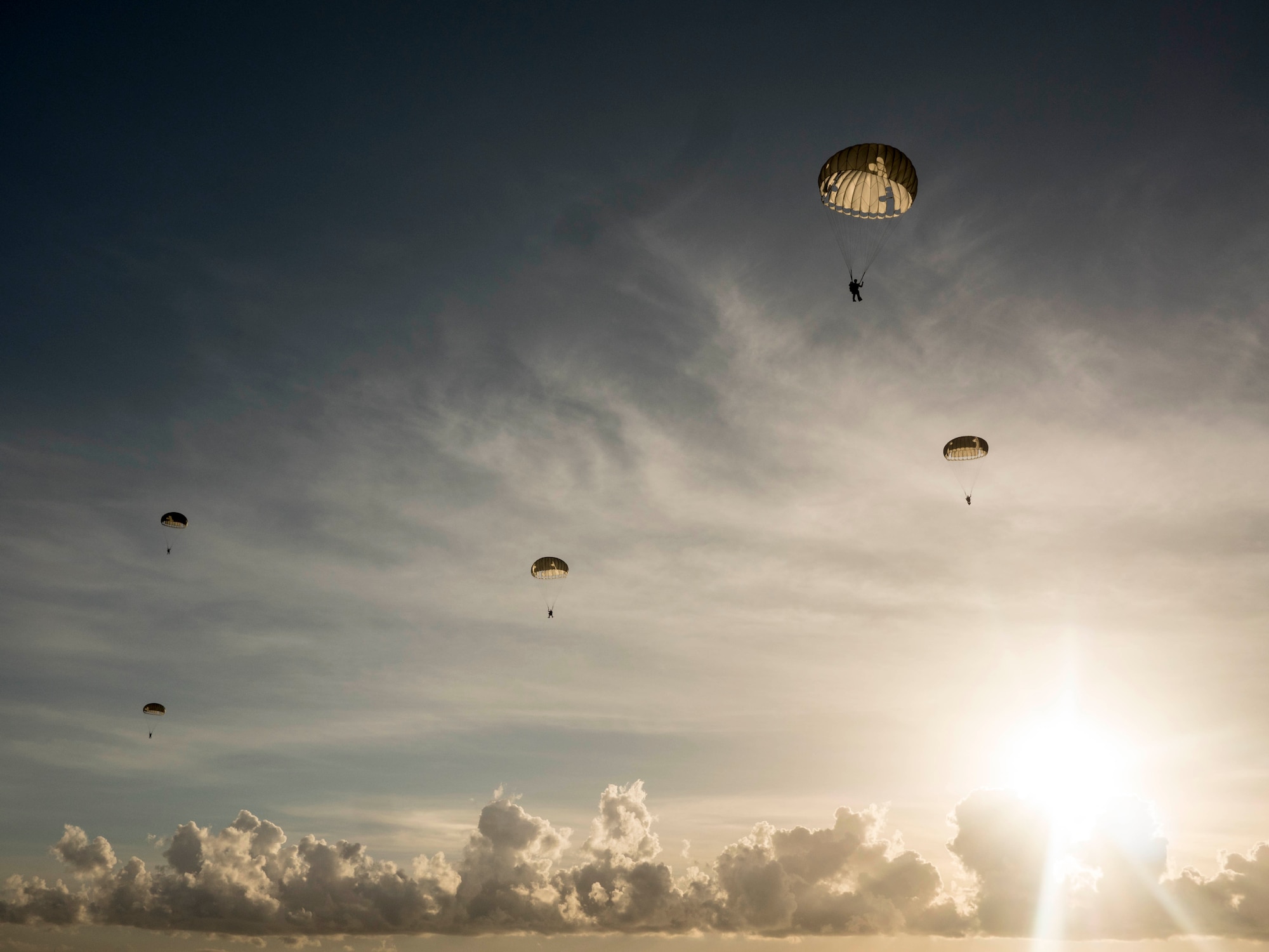 U.S. Air Force pararescumen, from the 31st rescue squadron, Kadena Air Base, Japan, float through the air after performing a static line jump from an MC-130J Commando, June 29, 2016, over the Pacific Ocean. Pararescuemen depend on the parachutes packed by expert air crew flight equipment personnel to be able to deploy anywhere to accomplish their mission. (U.S. Air Force photo by Senior Airman Omari Bernard)