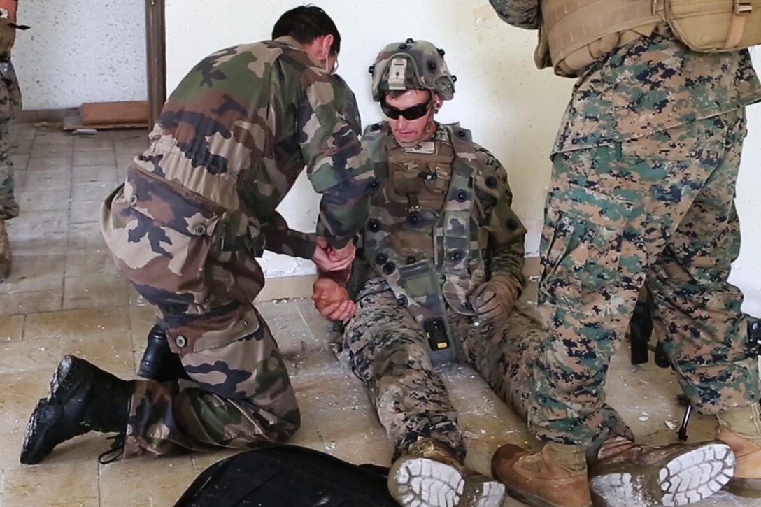 A French Army soldier treats a simulated wound on U.S. Marine Corps Lance Cpl. Kyle P. Ryan, a machine gunner with Charlie Compnay, 1st Battatlion 8th Marine Regiment, Special Purpose Marine Air-Ground Task Force-Crisis Response-Africa during a combined arms attack aboard Camp Sissonne, France, June 21, 2016. CENZUB provided SPMAGTF-CR-AF Marines with the ability to maintain their proficiencies in urban combat and integrate with French personnel and assets in a realistic scenario. (U.S. Marine Corps photo by Sgt. Kassie McDole/Released.) 