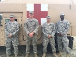 The four Massachusetts Guard members who saved a New Jersey woman from her stranded Cadillac pose in front of an ambulance.