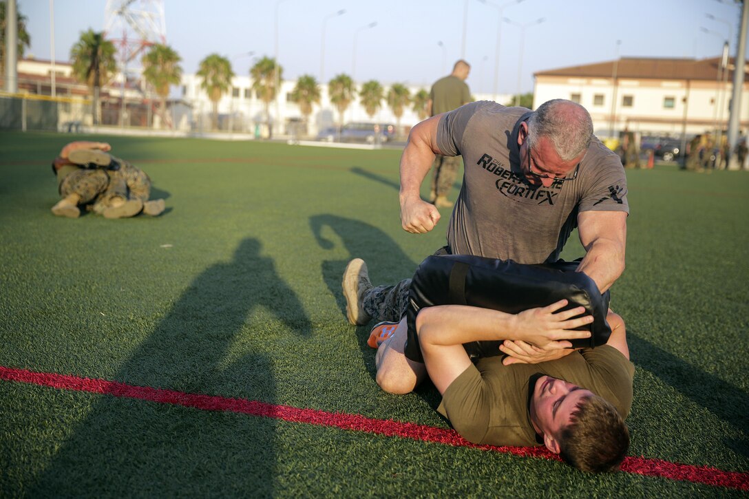 Celebrity Chef Robert Irvine and Cpl. Matthew Heldt, a ground radio repair technician with Special Purpose Marine Air-Ground Task Force Crisis Response-Africa, conduct Marine Corps Martial Arts Program techniques during a physical training event at Naval Air Station Sigonella, Italy, July 28, 2016.  Marines completed a circuit course with Irvine, which included upper and lower body workouts, MCMAP techniques and laps around the baseball field.  (U.S. Marine Corps photo by Cpl. Alexander Mitchell/released)