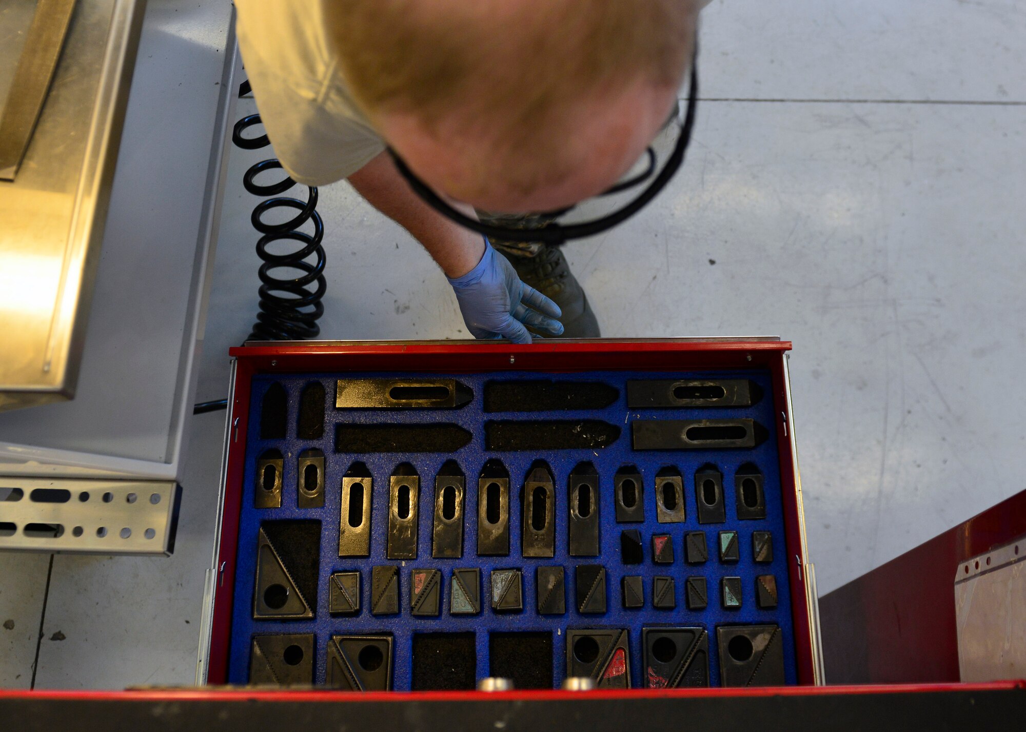 Master Sgt. Kyle Eickhoff, 31st Maintenance Squadron Metals Technology section chief, selects a machining clamp, July 27, 2016, at Aviano Air Base, Italy. Clamps are used in computer numeric control machines to hold metal in place before it’s cut. (U.S. Air Force photo by Airman 1st Class Cary Smith/Released) 