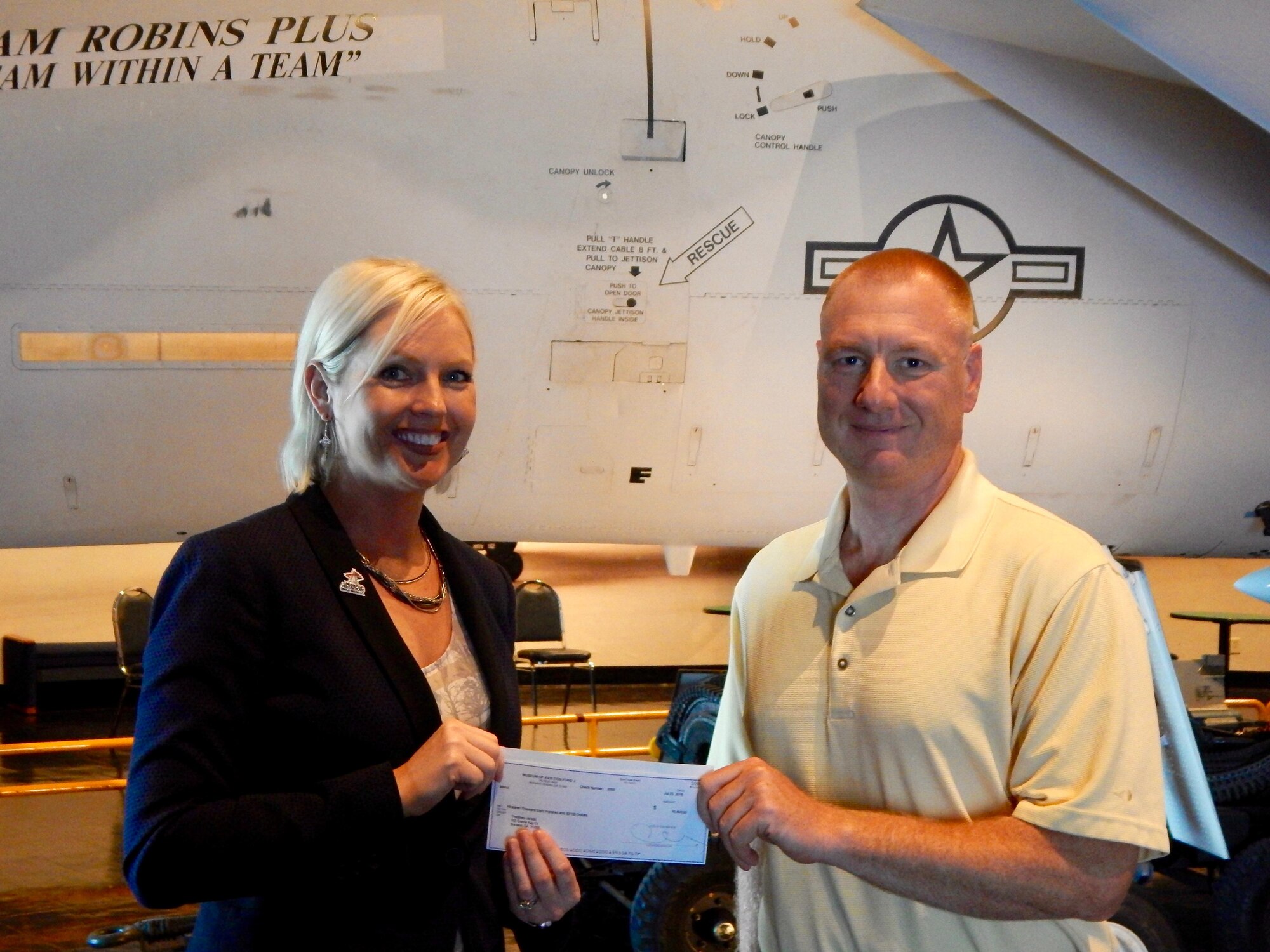 Chrissy Miner, Museum of Aviation Foundation president, presents Lt. Col. (Dr.) Ted Janicki, executive officer to Lt. Gen. Maryanne Miller, Air Force Reserve Command commander, with a $30,000 check for winning the Museum of Aviation's 31st Annual Auction, Raffle and Taste of Local Cuisine event in Warner Robins, Georgia, July 23. (Courtesy photo)