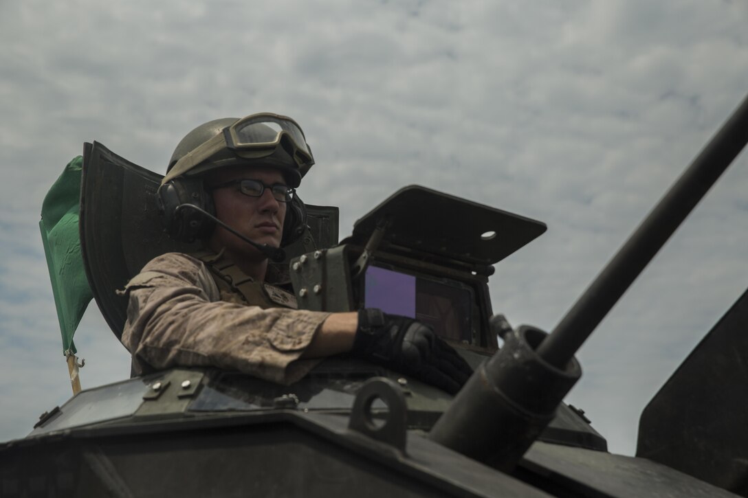 Lance Cpl. Kevin Christ, a crewman with Alpha Company, 2nd Assault Amphibian Battalion, spots targets downrange during a live-fire gunnery range at Camp Lejeune, N.C., July 27, 2016. With a max possible score of 1,000, Marines must fire through ten separate engagements compiling a score of 700 to pass.