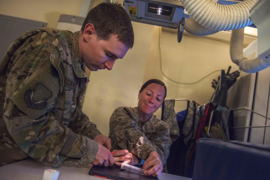 Air Force Staff Sgt. Keenan Dickens, left, repositions a patient's hand for an x-ray at Bagram Airfield, Afghanistan, July 20, 2016. Dickens is a diagnostic imaging technician assigned to the 455th Expeditionary Medical Group. Air Force photo by Senior Airman Justyn M. Freeman