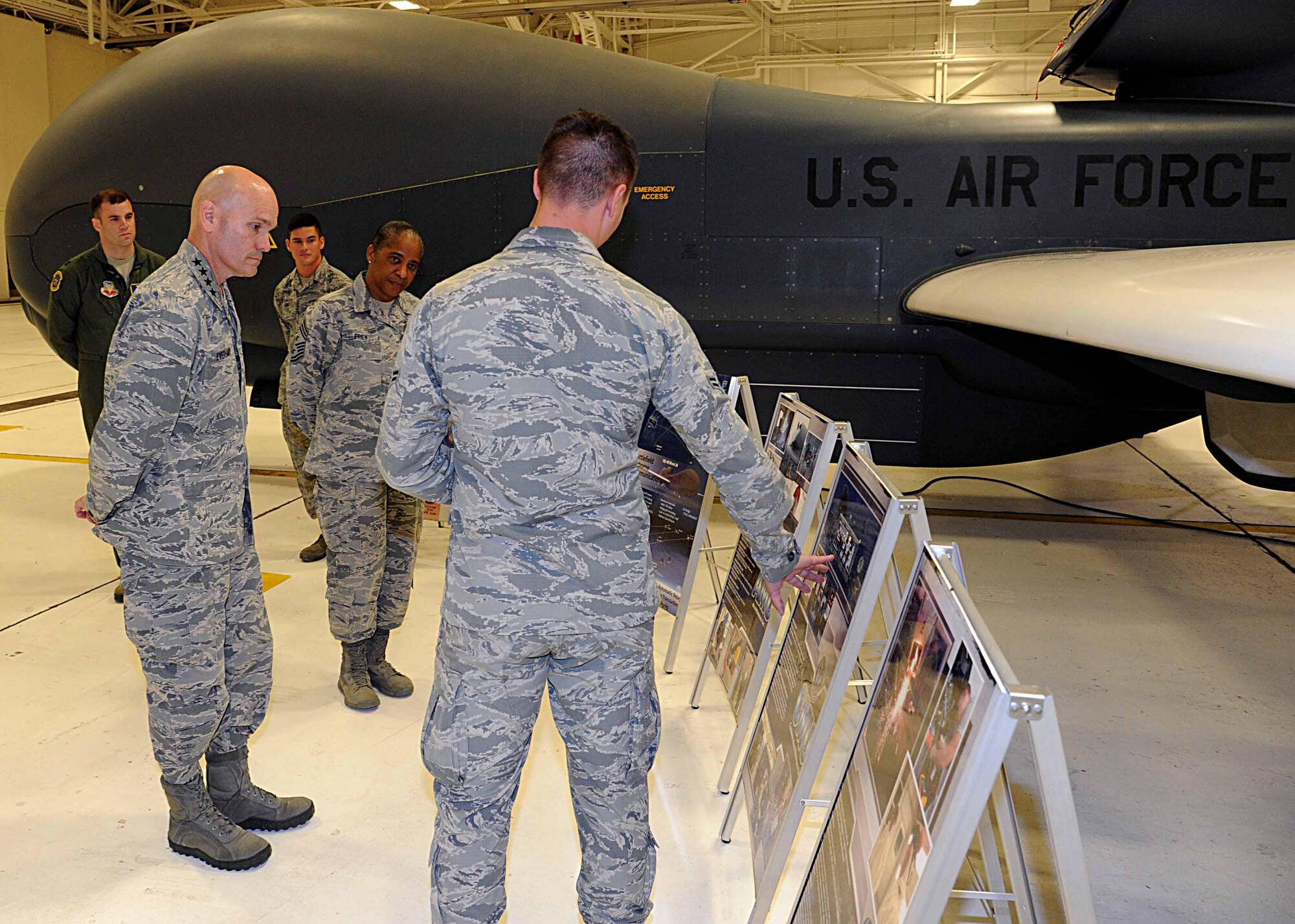 Gen. Carlton D. Everhart II, Air Mobility Command commander, left, and Chief Master Sgt. Shelina Frey, Air Mobility Command command chief, middle, listen to a briefing by Airman 1st Class Austin King, 69th Maintenance Squadron RQ-4B crew chief, July 28, 2016, on Grand Forks Air Force Base, N.D.  Everhart visited 69th Reconnaissance Group to learn about their mission during his tour of Grand Forks AFB. (U.S. Air Force photo by Senior Airman Ryan Sparks/Released)