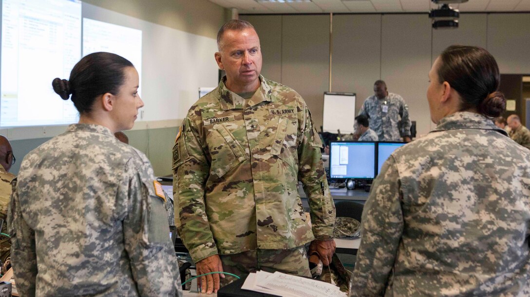 Brig. Gen. Vincent Barker, Commander 310th Sustainment Command (Expeditionary) receives a WAREX situation brief from Maj. Elizabeth Distler, 135th ESC (Constructive) commander and Maj. Destiny Scott, 135th ESC (Constructive) intelligence officer on July 11 at Fort McCoy, Wis. Distler and Scott participated in the WAREX Higher Lower Adjacent Supporting and Supported (HALSS) cell as part of annual training for the 310th ESC. (US Army Photo by Army Reserve Maj. Penny N. Zamora).