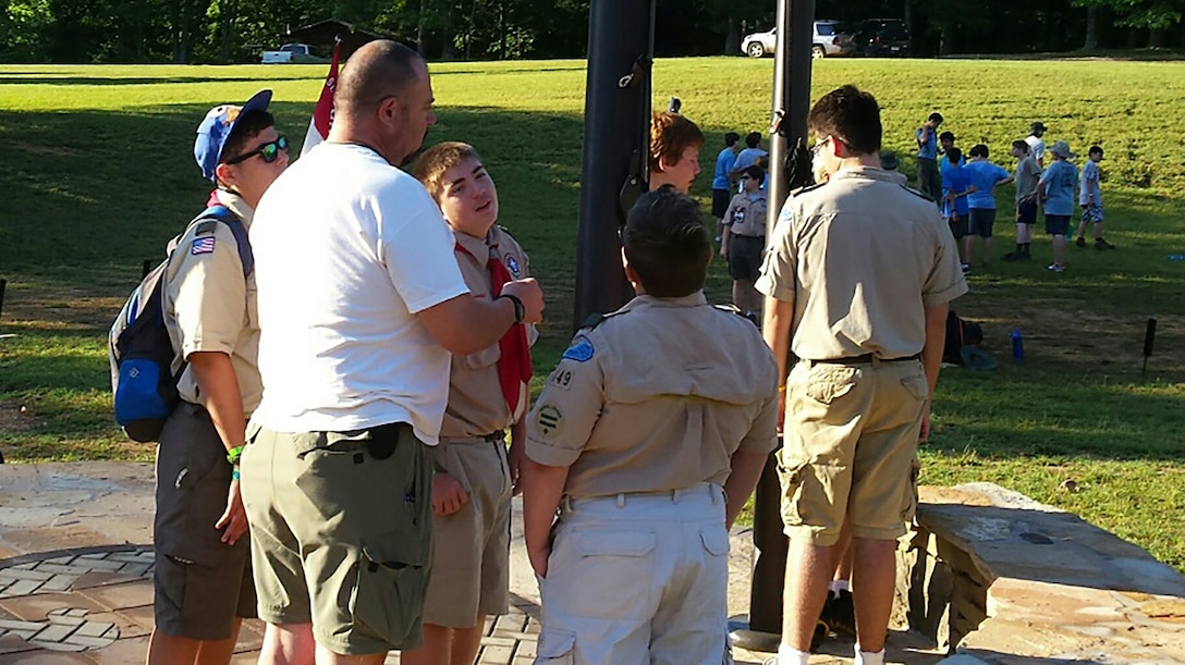 Boy Scouts Troop 149 Scoutmaster Dave Robinson discusses how to properly raise the flags June 30, 2016 during a Boy Scouts summer camp at Kia Kima Scout Reservation in Hardy, Ark.