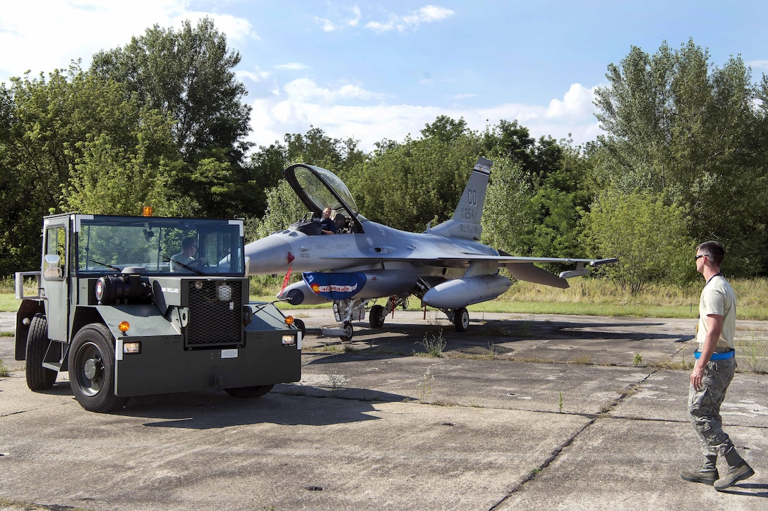 Air Force airmen tow an F-16 Fighting Falcon aircraft for maintenance at Papa Air Base, Hungary, July 19, 2016. Air National Guard photo by Senior Master Sgt. John Rohrer