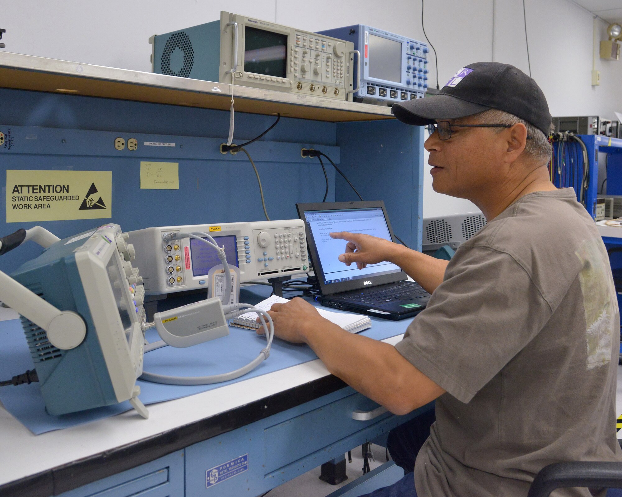 Stan Lopez, a technician with the Kirtland Precision Measurement Equipment Laboratory, closely follows a digital technical order while calibrating an oscilloscope. (Photo by Jamie Burnett)