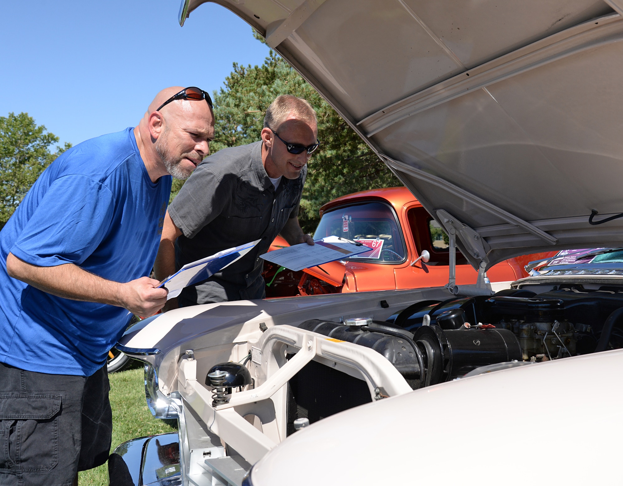 Judges Jason Carrion and John Sowder inspect the original 392 Hemi-engine on a 1957 Chrystal Imperial LeBaron owned by Jerry England. (U.S. Air Force photo by Alex R. Lloyd)