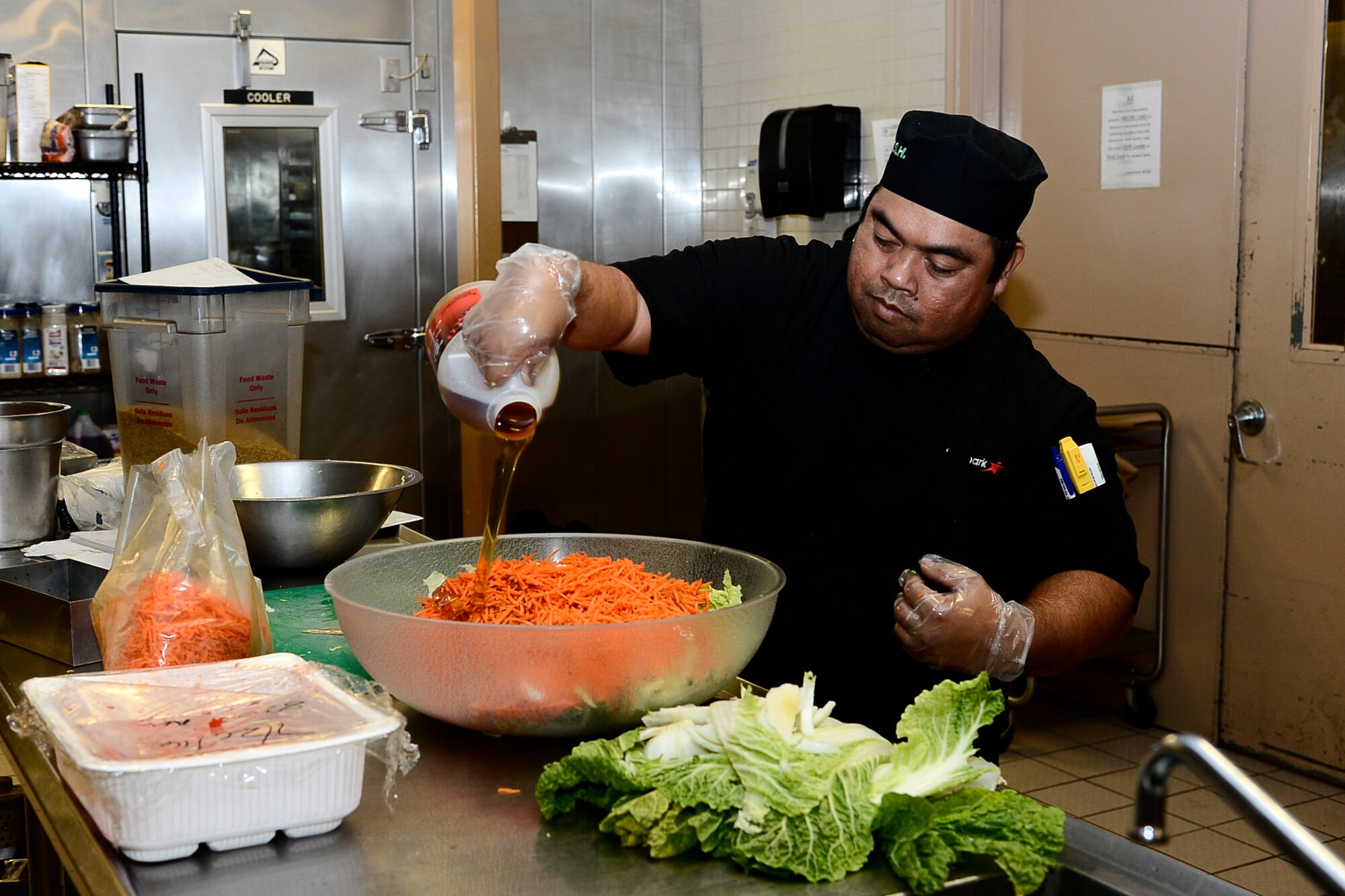 Nito Etang, a food specialist assigned to the 6th Force Support Squadron, prepares coleslaw for a Taco del Seoul themed lunch at MacDill Air Force Base, Fla., July 26, 2016. Dining facility members follow recipe cards to ensure consistent food preparation. (U.S. Air Force photo by Senior Airman Tori Schultz)