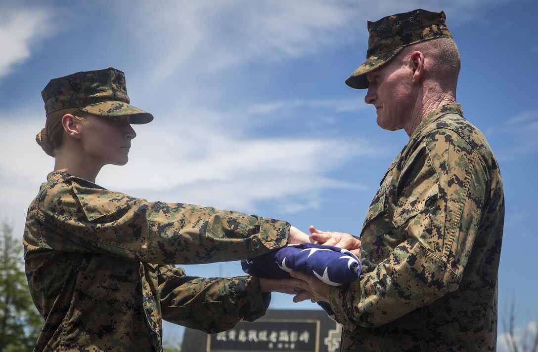 Lance Cpl. Elizabeth Diamond, left, presents the Colors to Sgt. Maj. Paul McKenna at the top of Mt. Suribachi on Iwo To, Japan. Roughly 20 Marines and Sailors hiked four miles to the summit of Mt. Suribachi to experience the terrain and gain an understanding of what the Marines and Sailors who came before went through during the Battle of Iwo Jima in World War II. Diamond is a barracks manager at the Training and Education Command, and McKenna is the U.S. Marine Corps Forces, Pacific sergeant major. (U.S. Marine Corps photo by Sgt. Matthew J. Bragg)