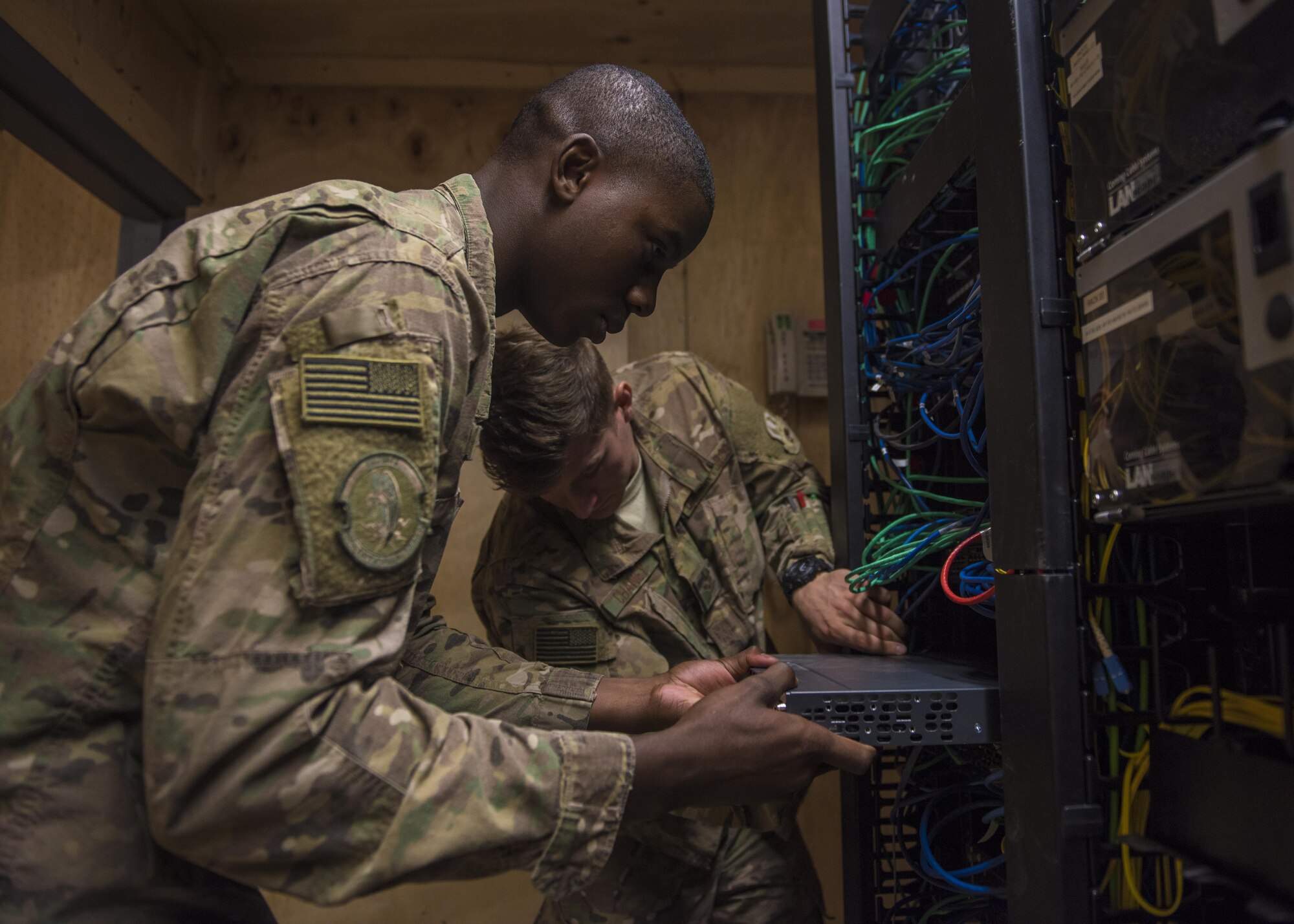 Senior Airman Isiah Chaney and Airman 1st Class Reginald Maffett, 455th Expeditionary Communications Squadron, network management technicians, install a switch, Bagram Airfield, Afghanistan, July 29, 2016. Switches provide network connectivity to devices such as phones and computers. (U.S. Air Force photo by Senior Airman Justyn M. Freeman)