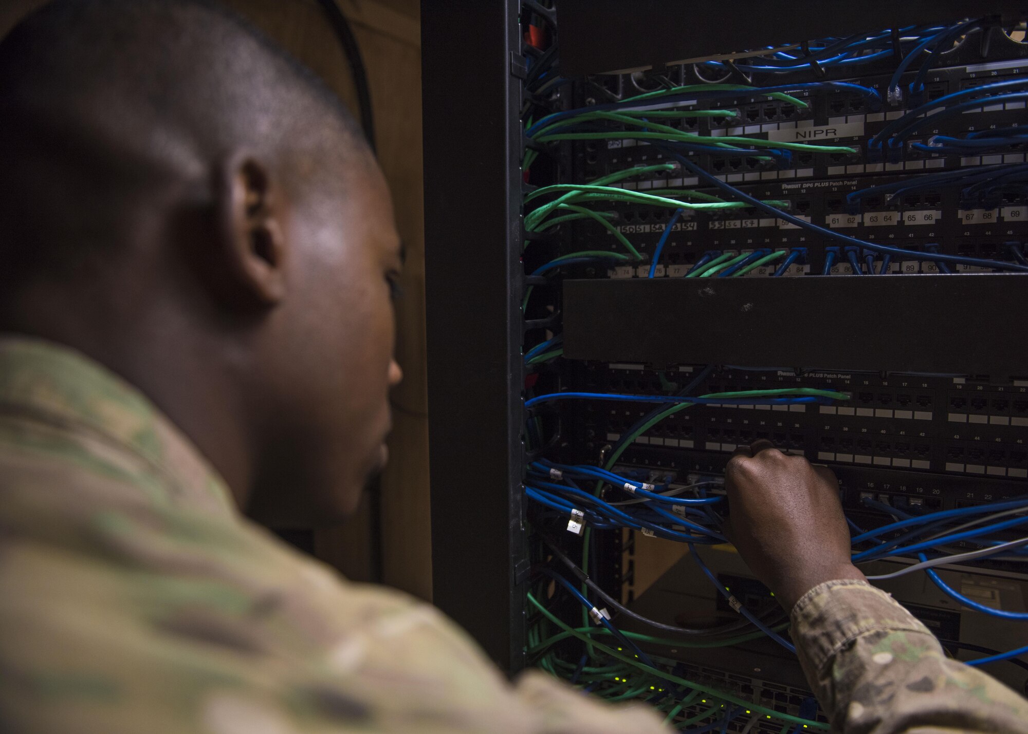 Airman First Class Reginald Maffett, 455th Expeditionary Communications Squadron, network management technician, connects wires to a network switch, Bagram Airfield, Afghanistan, July 29, 2016. The network management team manages network connectivity and sustains the base’s communications circuits. (U.S. Air Force photo by Senior Airman Justyn M. Freeman)