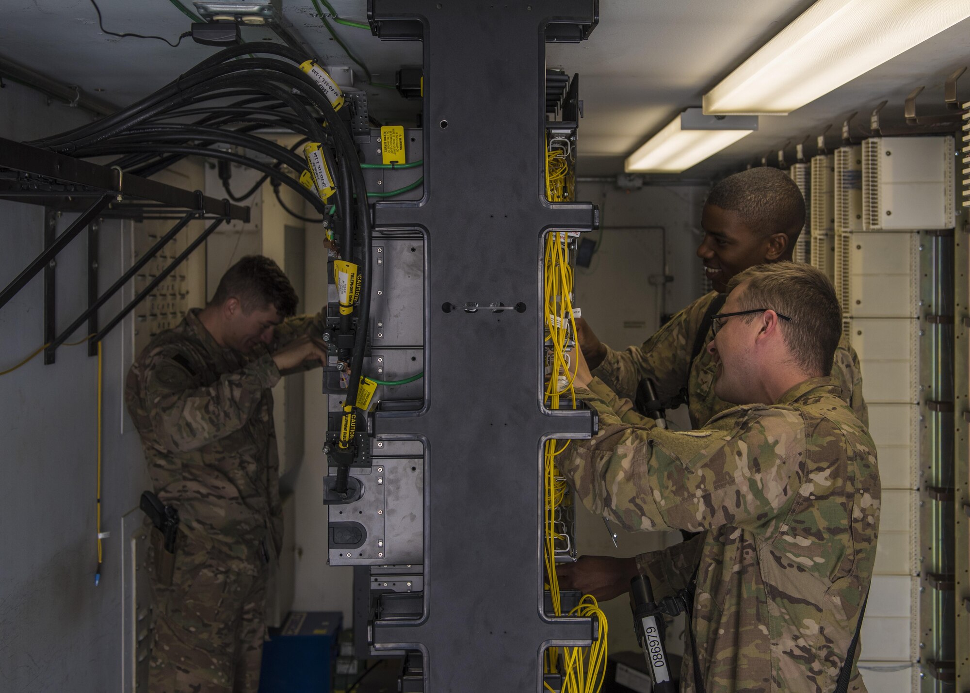 Senior Airman Isiah Chaney (left), Senior Airman Christopher Collins (front), and Airman 1st Class Reginald Maffett (back), 455th Expeditionary Communications Squadron, network management technicians, remove unused network cables, Bagram Airfield, Afghanistan, July 29, 2016. Network management technicians terminate, fabricate, and interconnect the network wiring throughout the base. (U.S. Air Force photo by Senior Airman Justyn M. Freeman)