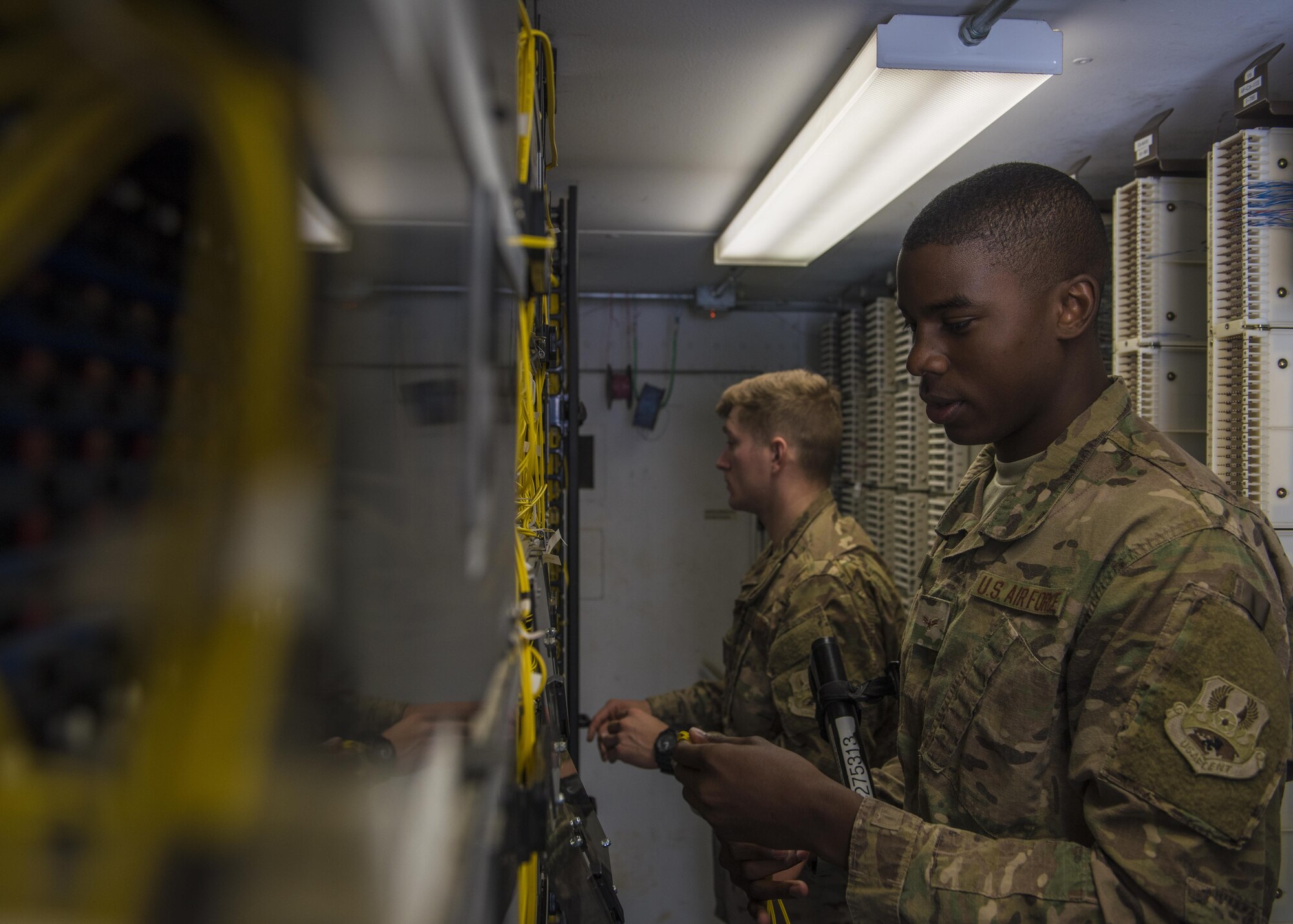 Senior Airman Isiah Chaney and Airman 1st Class Reginald Maffett, 455th Expeditionary Communications Squadron, network management technicians, locate and remove old network links, Bagram Airfield, Afghanistan, July 29, 2016. The network management shop provides a balance of network distribution and usage by maintaining old and new connectivity links. (U.S. Air Force photo by Senior Airman Justyn M. Freeman)