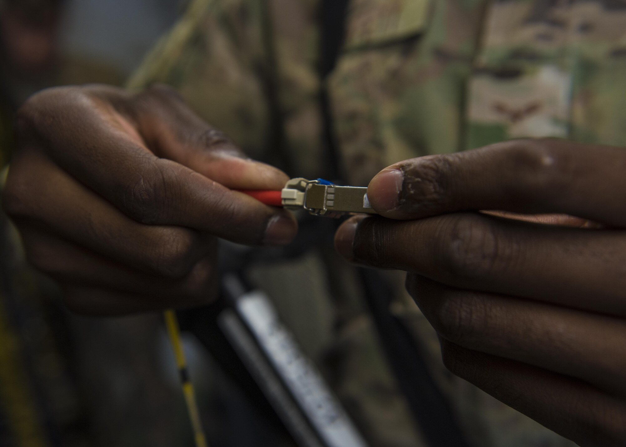 Airman 1st Class Reginal Maffett, 455th Expeditionary Communications Squadron, network management technician, connects a gigabit interface converter to a fiber link, Bagram Airfield, Afghanistan, July 29, 2016. GBICs allow technicians to configure and upgrade electro-optical communications networks, providing more bandwidth to Bagram network users. Network technicians manually join every computer onto their wireless network and closely control bandwidth usage to help ensure all base users have network access. (U.S. Air Force photo by Senior Airman Justyn M. Freeman)