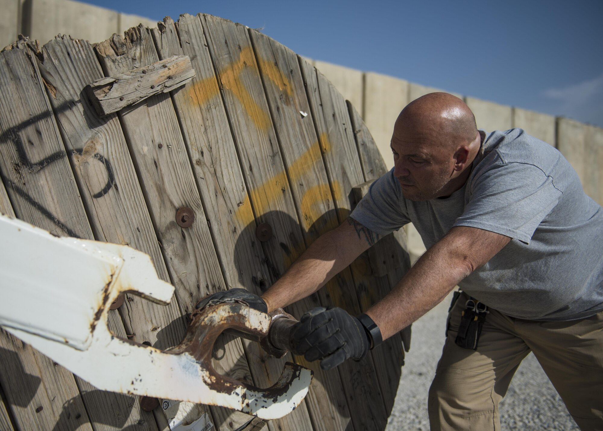 Patrick Casket, 455th Expeditionary Communications Squadron, cable and antenna technician, inserts a pole into a cable reel, Bagram Airfield, Afghanistan, July 30, 2016. A load of 144 strand fiber cable will be transported and used to expand network capabilities on the south side of base. (U.S. Air Force photo by Senior Airman Justyn M. Freeman)