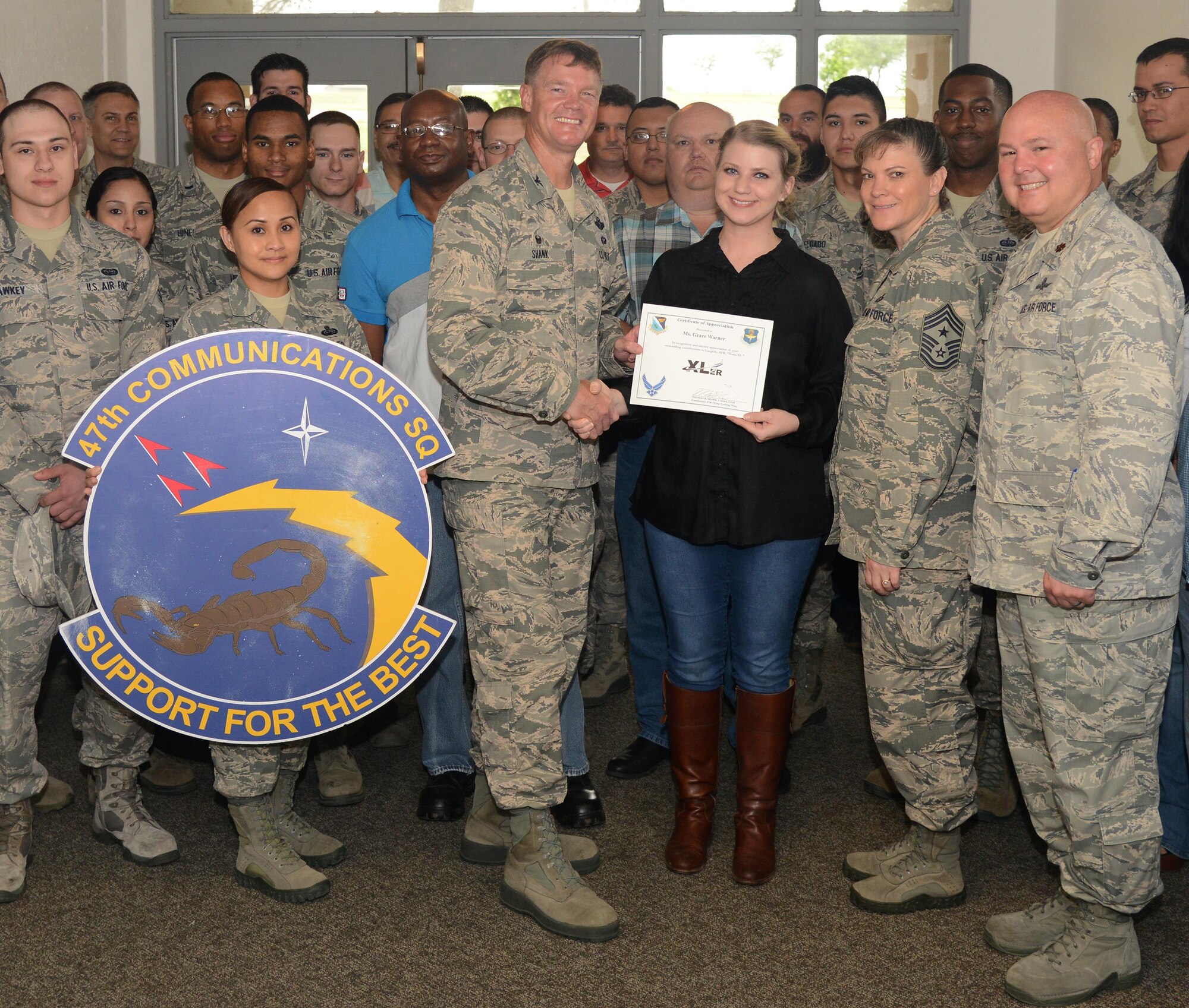 Grace Warner, 47th Communications Squadron assistant information systems security manager, accepts the “XLer of the Week” award from Col. Thomas Shank, left, 47th Flying Training Wing commander, and Chief Master Sgt. Teresa Clapper, right, 47th FTW command chief, here, May 24, 2016. The XLer is a weekly award chosen by wing leadership and is presented to those who consistently make outstanding contributions to their unit and Laughlin. (U.S. Air Force photo/Airman 1st Class Brandon May)