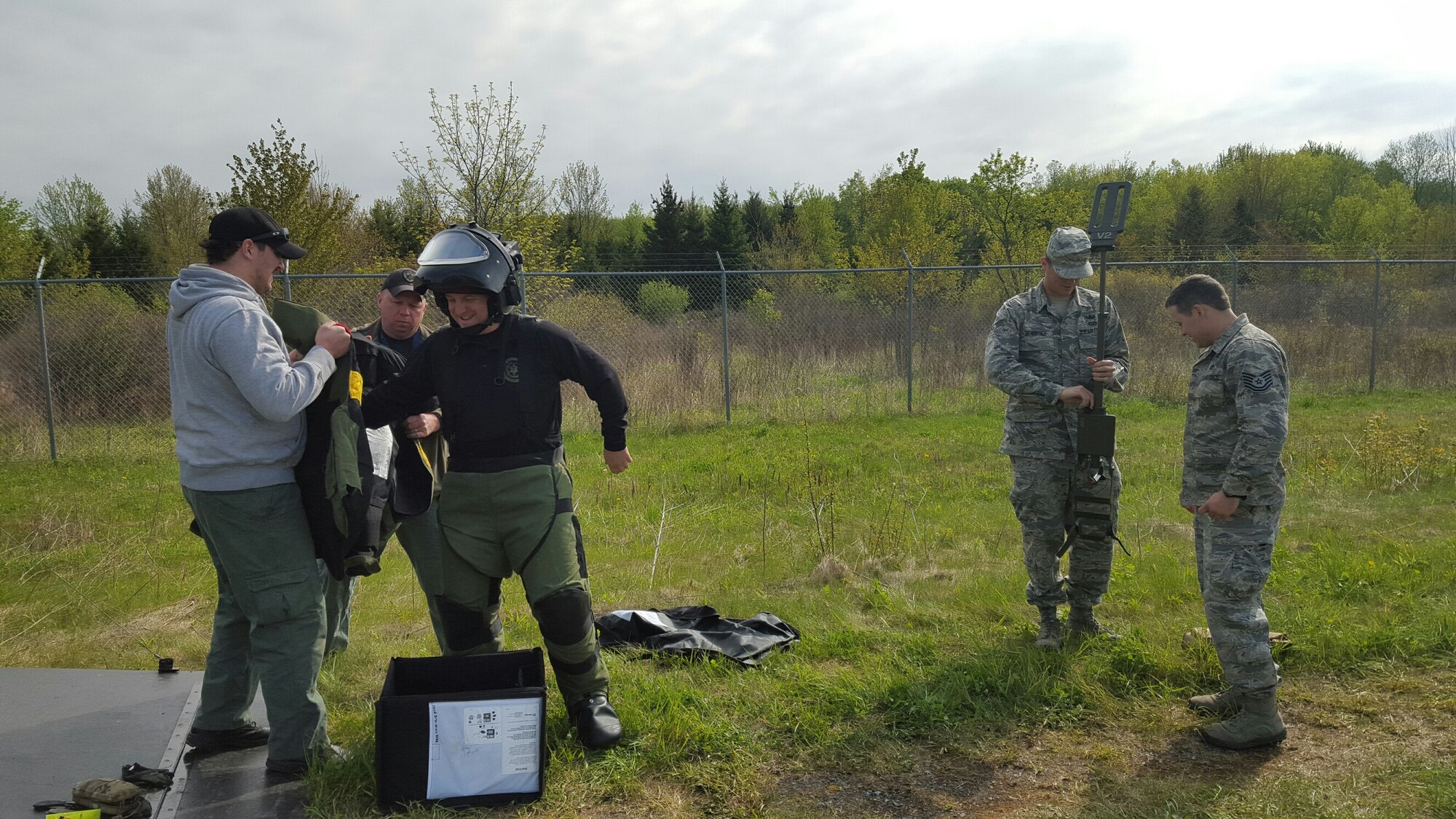 Erie County Bomb Squad members outfit Bomb Squad Commander Daniel Walczak in an Explosive Ordnance Disposal 9 Bomb Suit while SrA Justin Devantier, EOD team member, 914th Civil Engineer Squadron, and Tech. Sgt. Aaron Clark, EOD team leader, 914th Civil Engineer Squadron, prepare a metal detector for operation. The members participated in an inter-agency, improvised explosive device training event known as the Ravens Challenge which was held from May 16-20, 2016 in Oriskany, NY. (U.S. Photo by Tech. Sgt. Adam Clement/released)